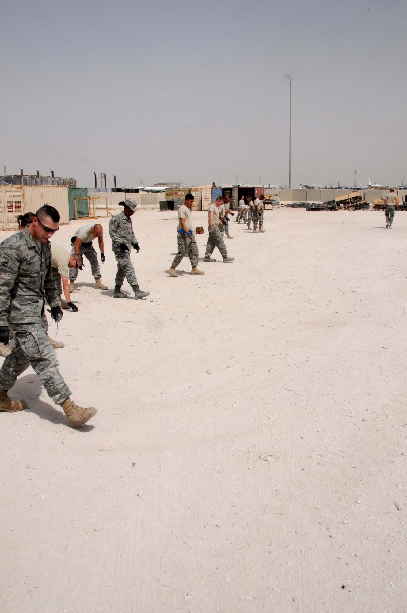 Airmen from the 379th Expeditionary Logistics Readiness Squadron conduct a foreign object debris walk April 1 in Southwest Asia.  The yard is being cleared as the 379 ELRS prepares to move to a new location.  (U.S. Air Force photo/ Staff Sgt. Anthony Graham)