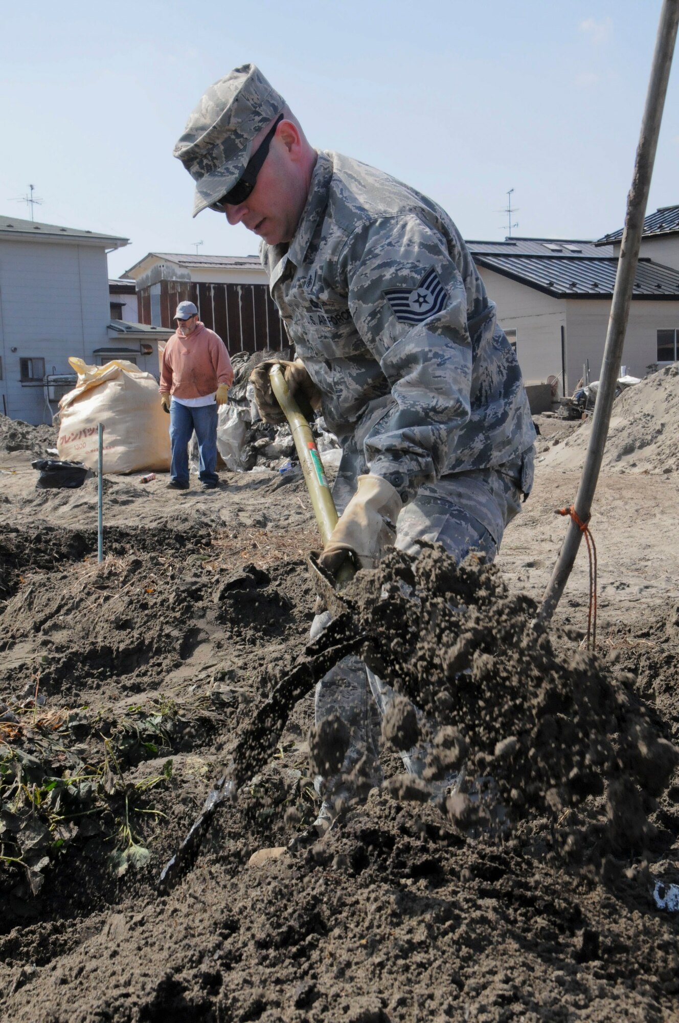 HACHINOHE, Japan -- A U.S. Air Force Airman from Misawa Air Base digs through a strawberry field looking for debris, here April 1. Approximately two busloads of volunteers visited the Hachinohe strawberry fields every day during the week to assist local farmers with cleaning up the destruction left by a tsunami. (U.S. Air Force photo by Staff Sgt. Rachel Martinez/Released)