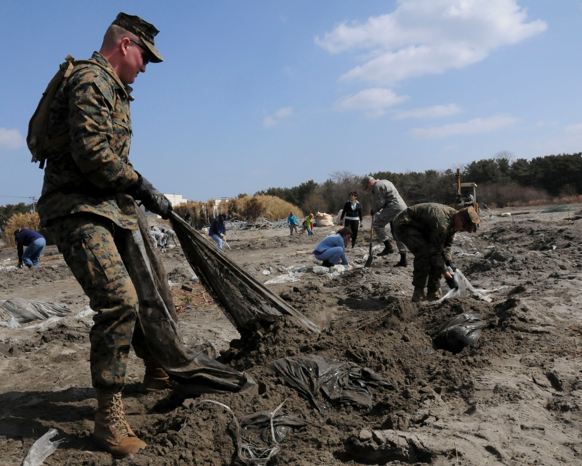HACHINOHE, Japan -- U.S. Marine Corp Lance Cpl. William Deane, temporarily assigned to Misawa Air Base from the Combat Logistics Regiment-3 at Camp Foster, Okinawa, pulls plastic sheeting out of dirt and sand at a strawberry field, here April 1. Misawa Helps, a command-sponsored volunteer project, sent 75 Marines, Airmen, Sailors and civilians this day to help clear the strawberry farm of debris from the March 11 tsunami. (U.S. Air Force photo by Staff Sgt. Rachel Martinez/Released)