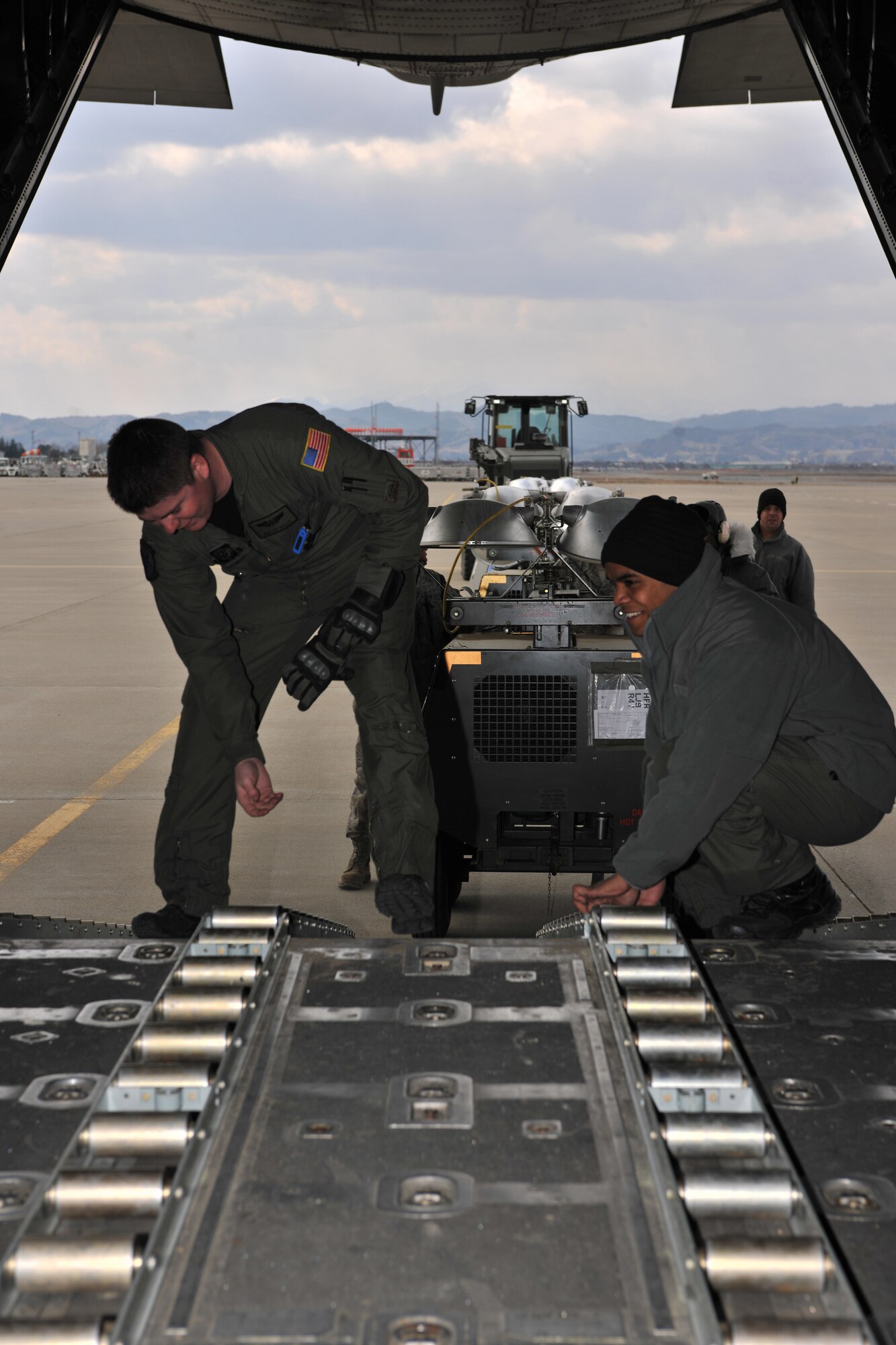 SENDAI AIRPORT, Japan -- Senior Airman J.T. Mills (left) and Senior Airman Jed Bilibei, 17th Special Operations Squadron loadmasters from Kadena Air Base, prepare to load flood lights onto a MC-130P Combat Shadow aircraft at Sendai Airport April 3. U.S. forces remain focused to help support the Japanese during relief efforts. (U.S. Air Force photo/Master Sgt. Kimberly Spinner) 