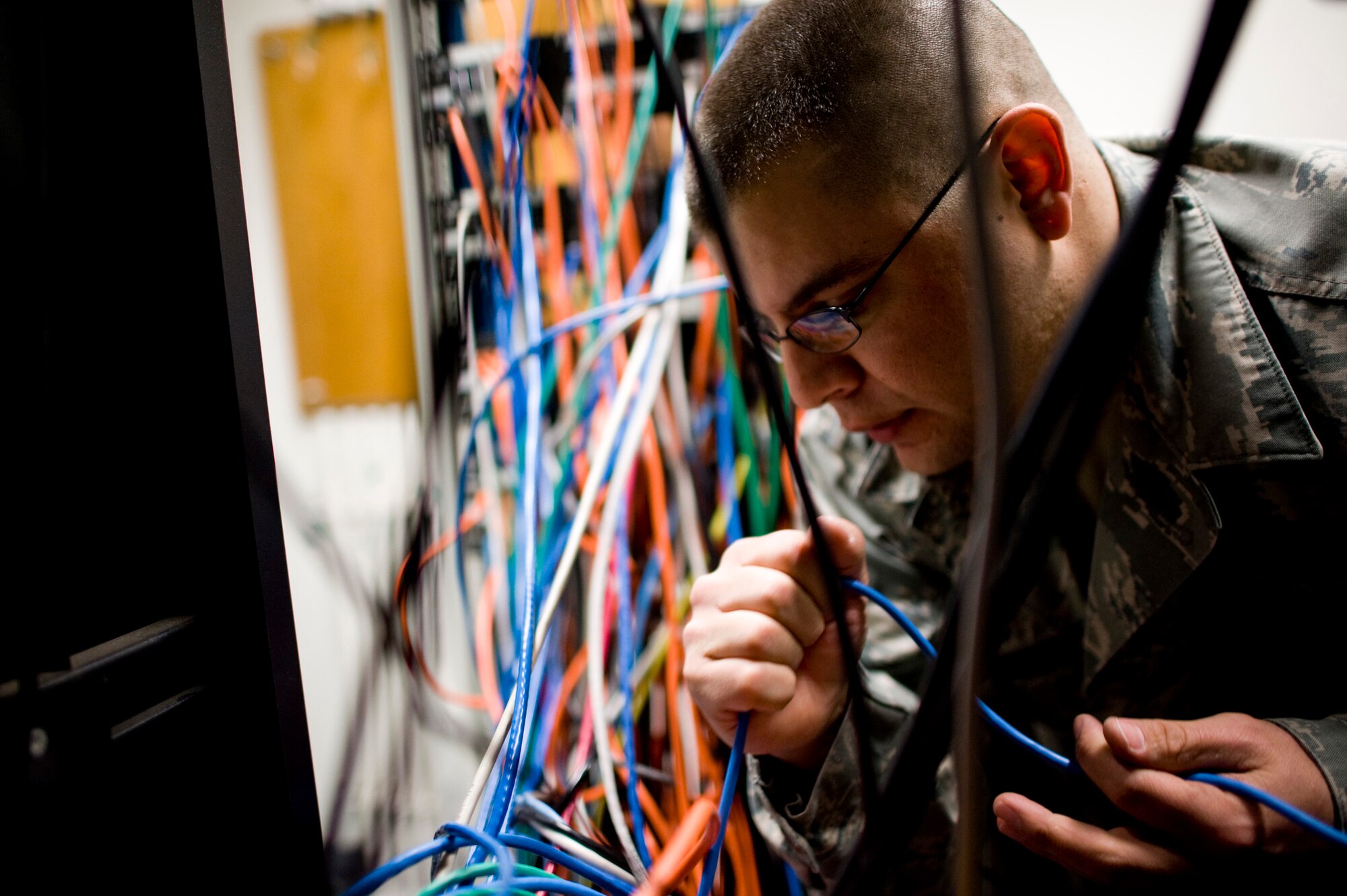 YOKOTA AIR BASE, Japan -- Tech. Sgt. Adrian Placencia, 374th Communications Squadron cyber transport technician, untangles wires in the communications room of the 36th Airlift Squadron building, Yokota Air Base, Japan, April 2, 2011. Sergeant Placencia helped install additional network connections to support Operation Tomodachi. (U.S. Air Force photo/Staff Sgt. Samuel Morse)
