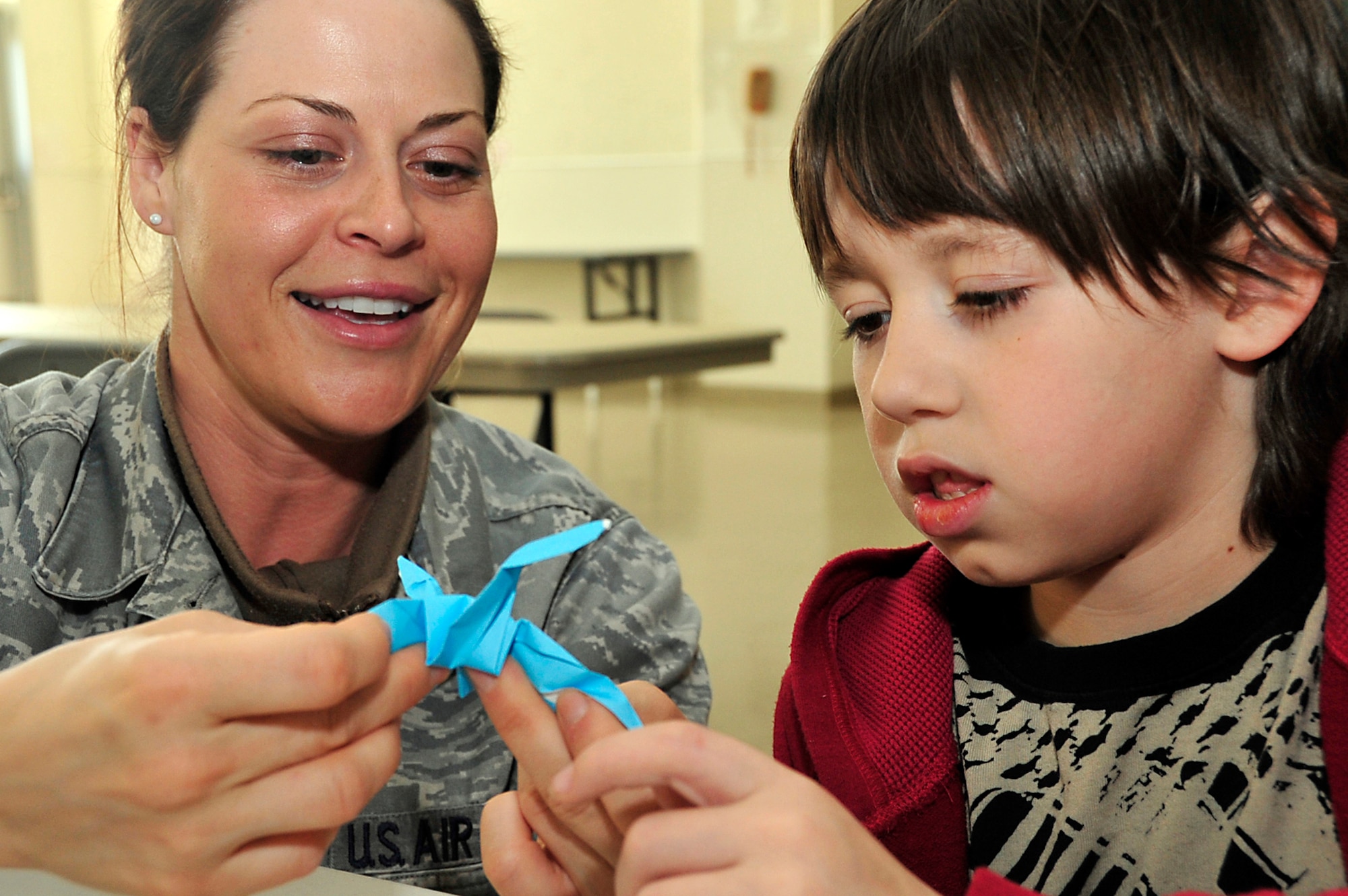 MISAWA AIR BASE, Japan -- Tech. Sgt. Amie Duley, 35th Medical Surgical Squadron, shows Darin Wesley, a third grade Sollars Elementary School student, how to make an origami crane April 6. The students are helping Students Rebuild to reach their goal of 100,000 submissions which will be woven into an art display at a reconstructed school in Sendai, Japan.  The project also helps Students Rebuild raise funds in support of their Japanese peers. Students Rebuild is a global organization that mobilizes young people to connect, learn and take action on critical global issues. (U.S. Air Force photo by Staff Sgt. Marie Brown\Released)