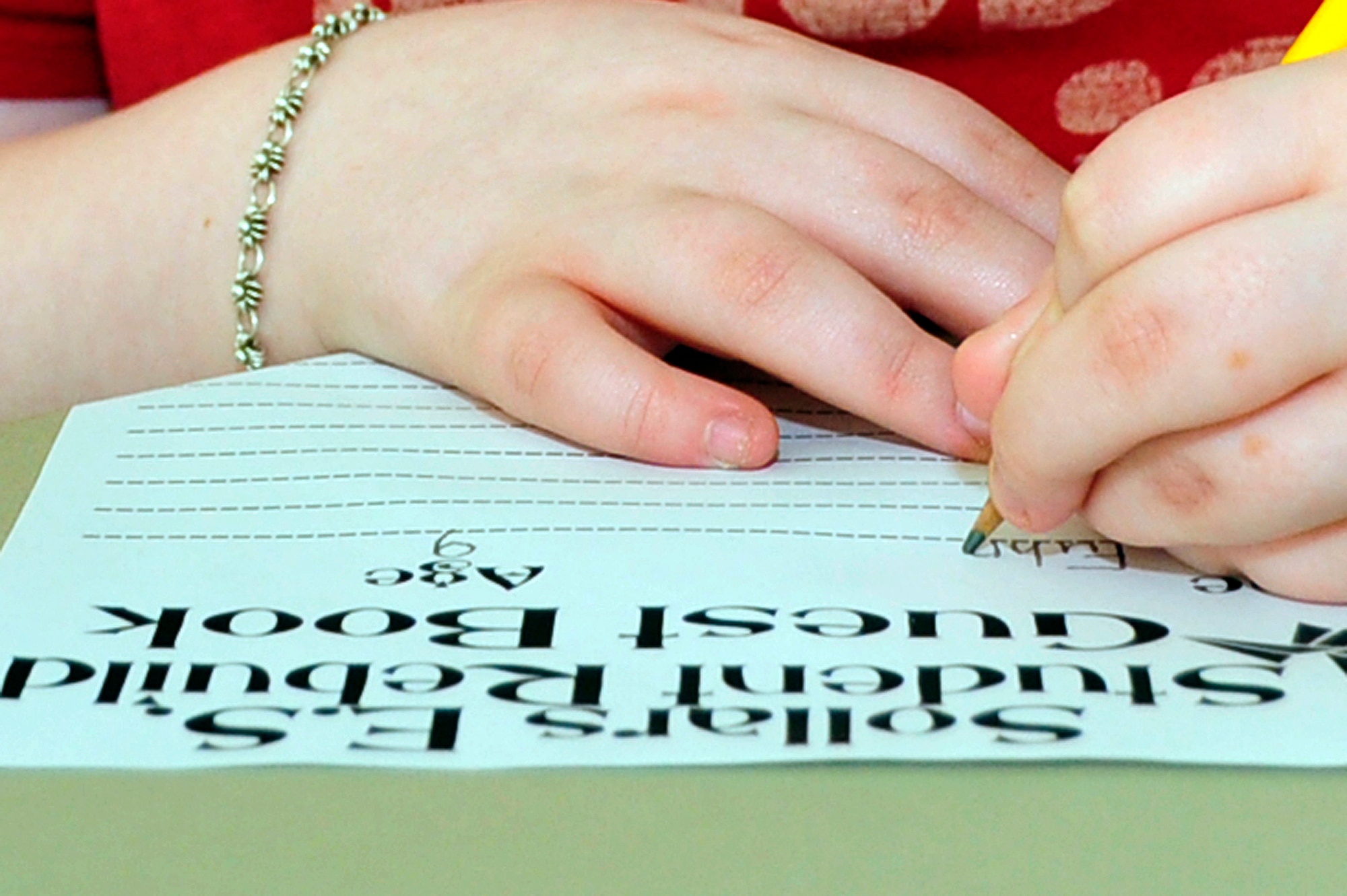 MISAWA AIR BASE, Japan -- Shawna Fuhrer, third grade student at Sollars Elementary School, signs in on a page of the guest book April 6 as part of a project to fold 100,000 origami cranes. The guest book along with all origami cranes will be sent to Students Rebuild to help raise funds in support of their Japanese peers. Students Rebuild is a global organization that mobilizes young people to connect, learn and take action on critical global issues. (U.S. Air Force photo by Staff Sgt. Marie Brown\Released)