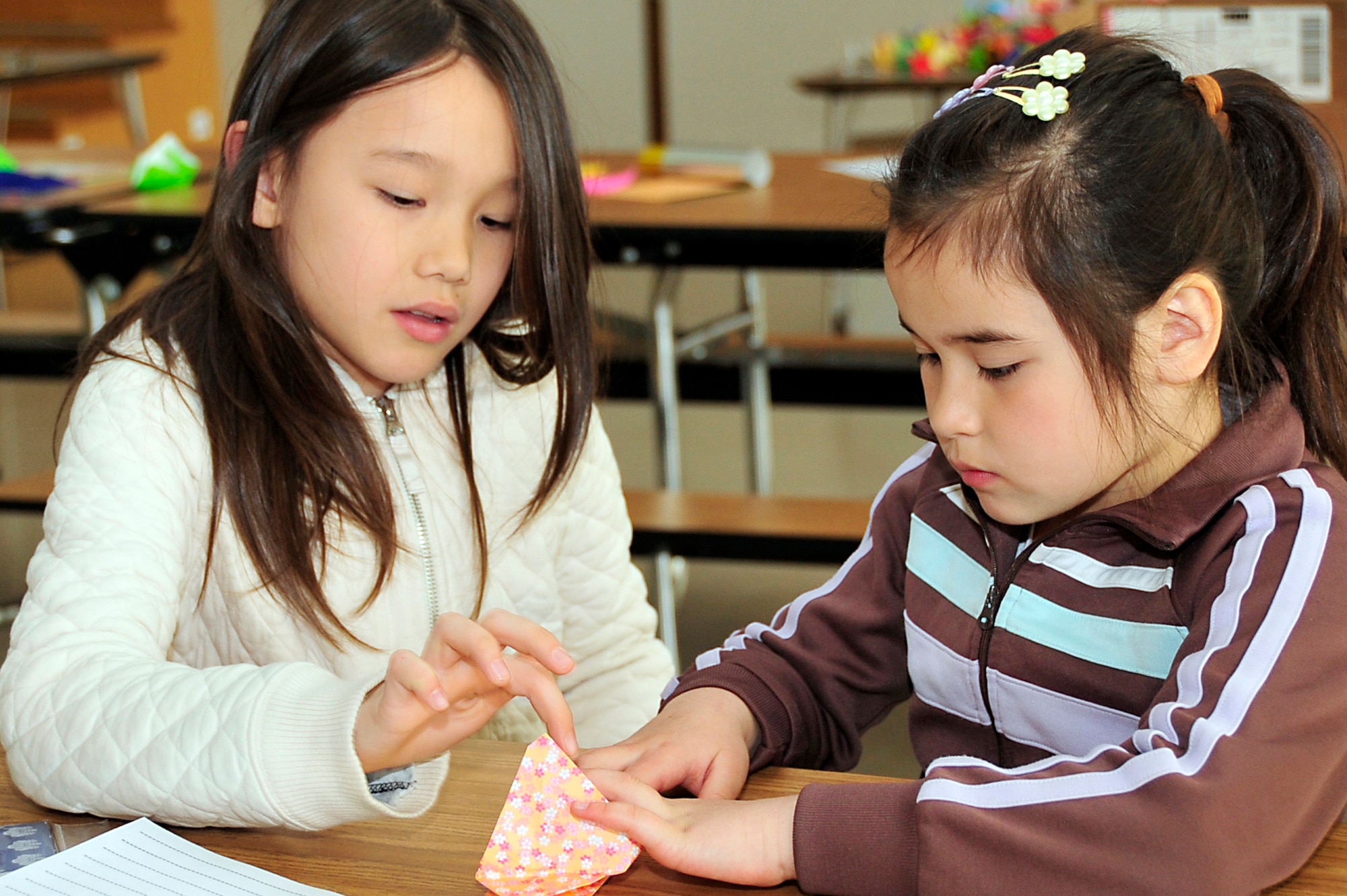 MISAWA AIR BASE, Japan -- Leah Flack, left and Laura Fox, third grade Sollars Elementary School students, work together to make an origami crane at Sollers Elementary School April 6. The cranes will be sent to Students Rebuild in order to help raise funds to support their Japanese peers. Students Rebuild is also working to collect 100,000 origami cranes from young people to represent 100 wishes of support and healing for Japan. Students Rebuild is a global organization that mobilizes young people to connect, learn and take action on critical issues.  (U.S. Air Force photo by Staff Sgt. Marie Brown\Released)