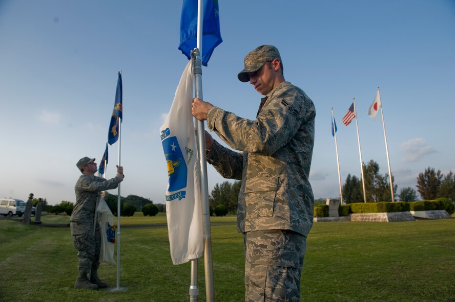 KADENA AIR BASE, Japan - Airman 1st Class Daniel Davis, 18th Component Maintenance Squadron, and Airman 1st Class Jordan Arnold, 353rd Special Operations Group, raise state flags at 18th Wing headquarters April 5. Airmen Davis and Arnold are part of the Kadena Pride Team responsible for cleaning up the base. (U.S. Air photo/ Staff Sgt. Jonathan Steffen)