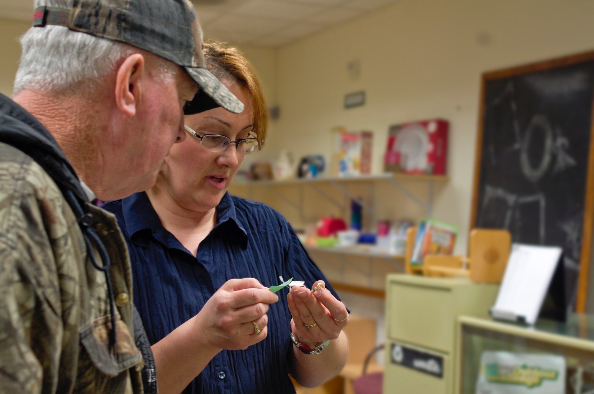 Carlee Lane shows Gary Templeton, customer, a piece of jewelry March 29, 2011 at the Thrift Shop here. Mrs. Lane is a volunteer with the Thrift Shop and Mr. Templeton is a customer of six years. He also consigns items here. Consignment contracts are available for 25 cents and 30 percent of the profit from sold consignment items are donated to charities and scholarship funds. (U.S. Air Force photo/Senior Airman Natasha E. Stannard)