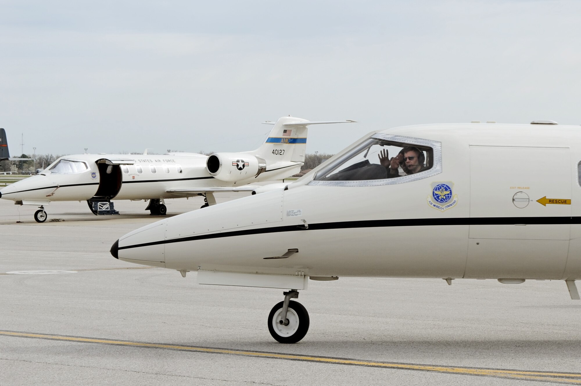 Capt. Luis Garces and Capt. Thomas Armstrong, both with the 458th Airlift Squadron's C-21A formal training unit, give a farewell greeting as they taxi out April 6, 2011 at Scott Air Force Base, Ill. Captain Garces trained Captain Armstrong during the initial qualification course under the 458th AS after it regained the C-21 training mission from the 45th AS at Kessler AFB, Miss. The C-21 training mission belonged to Scott until the early 1990s. (U.S. Air Force Photo/Staff Sgt. Brian J. Valencia)