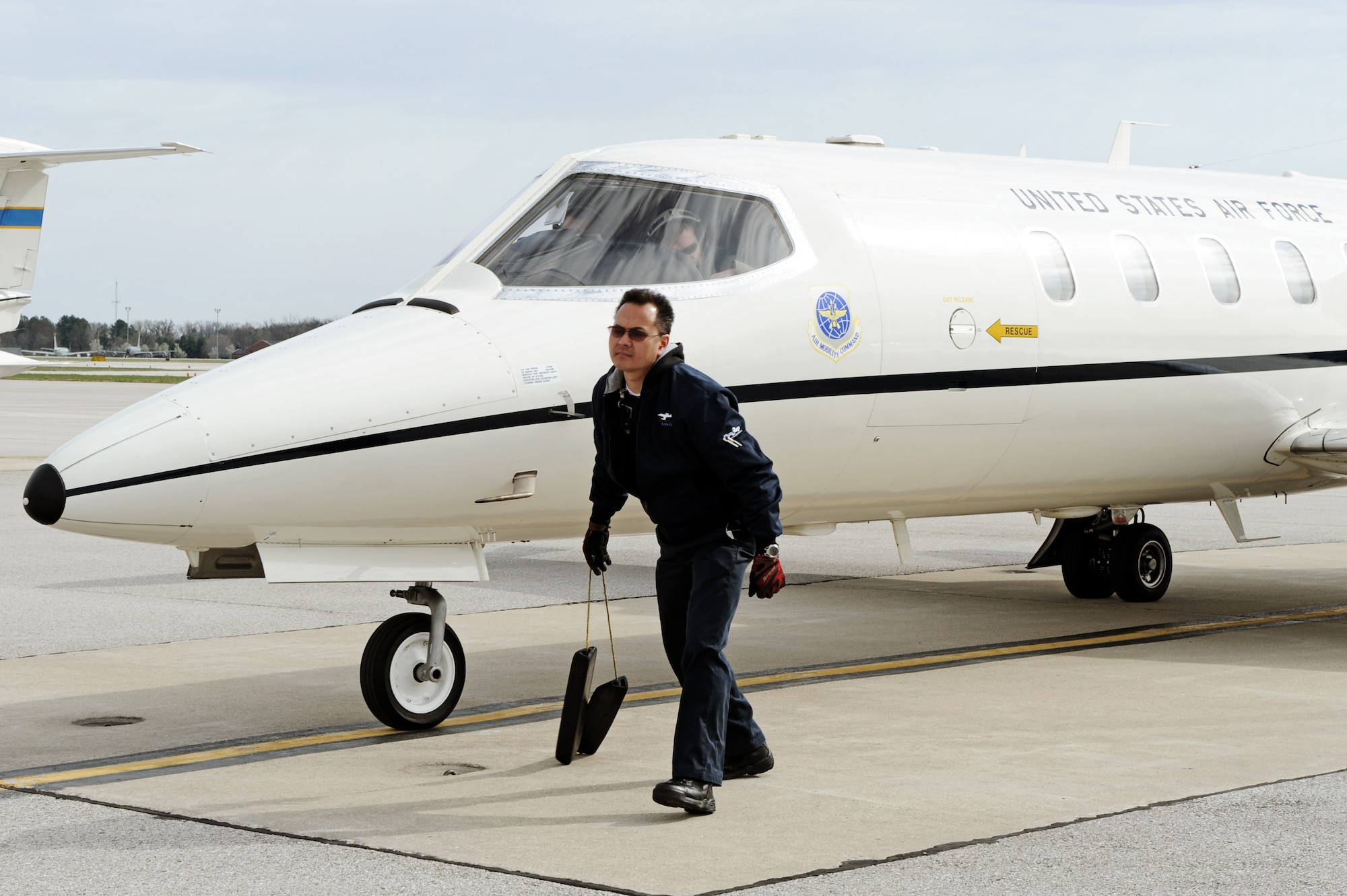 Steve Edwards, DynCorp International contractor, pulls the chalks from a C-21A prior to take-off April 6, 2011 at Scott Air Force Base, Ill. The C-21 was flown during the initial qualification course under the 458th AS after it regained the C-21 training mission from the 45th AS at Kessler AFB, Miss. The C-21 training mission belonged to Scott until the early 1990s. (U.S. Air Force Photo/Staff Sgt. Brian J. Valencia)