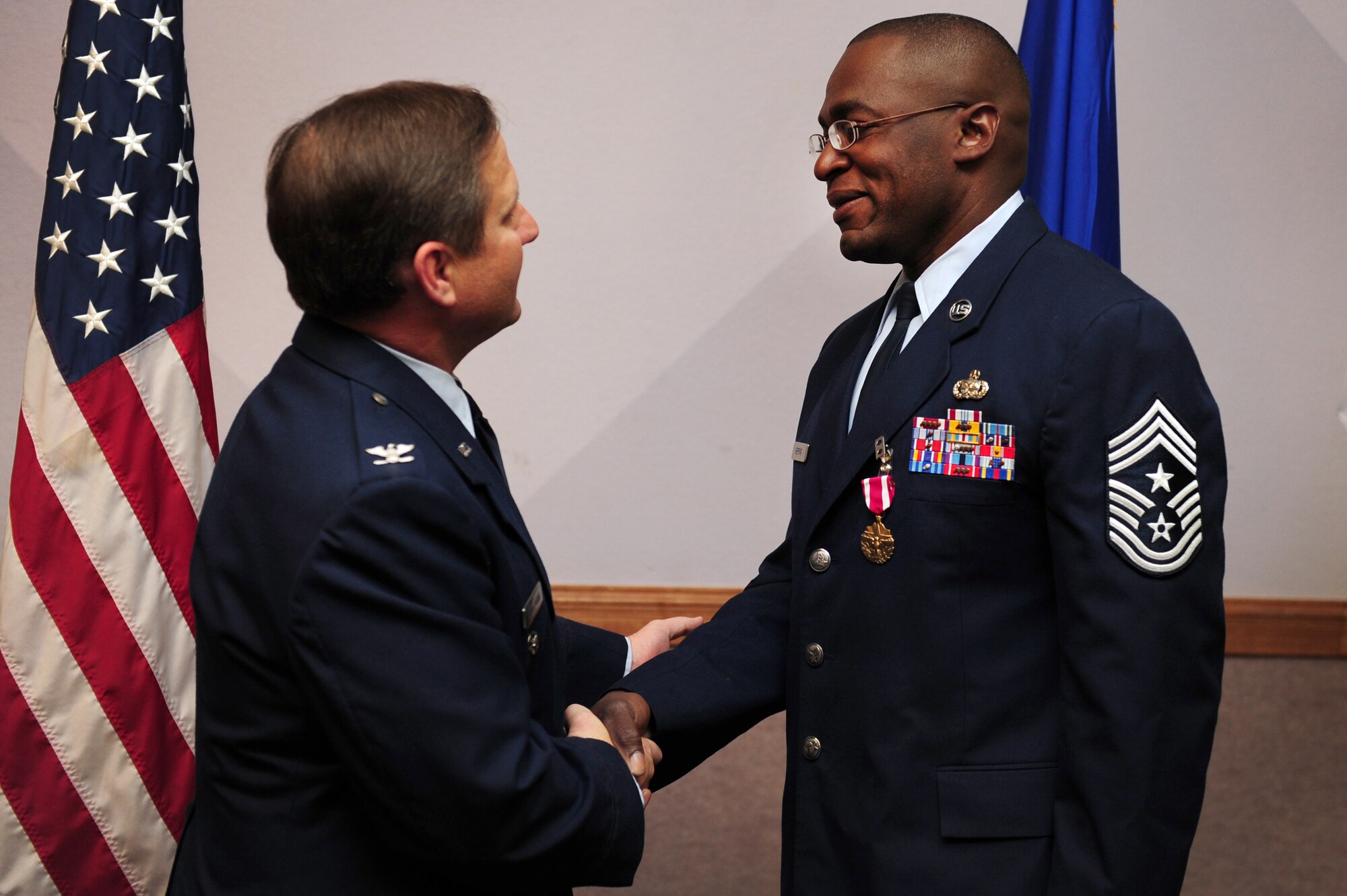 NELLIS AIR FORCE BASE, Nev. -- Col. Steven Winkleman, 99th Air Base Wing vice-commander, congratulates Chief Master Sgt. Alfred Herring after presenting him the Air Force Meritorious Service Medal March 31, at the 99th ABW monthly promotion ceremony. Chief Herring received the Meritorious Service medal for his two year service as the 99 ABW command chief. Chief Herring departed Nellis 2  April, to assume the role of command chief for the 9th Air Expeditionary Task Force in Afghanistan. (U.S. Air Force photo by Staff Sgt. William P. Coleman)