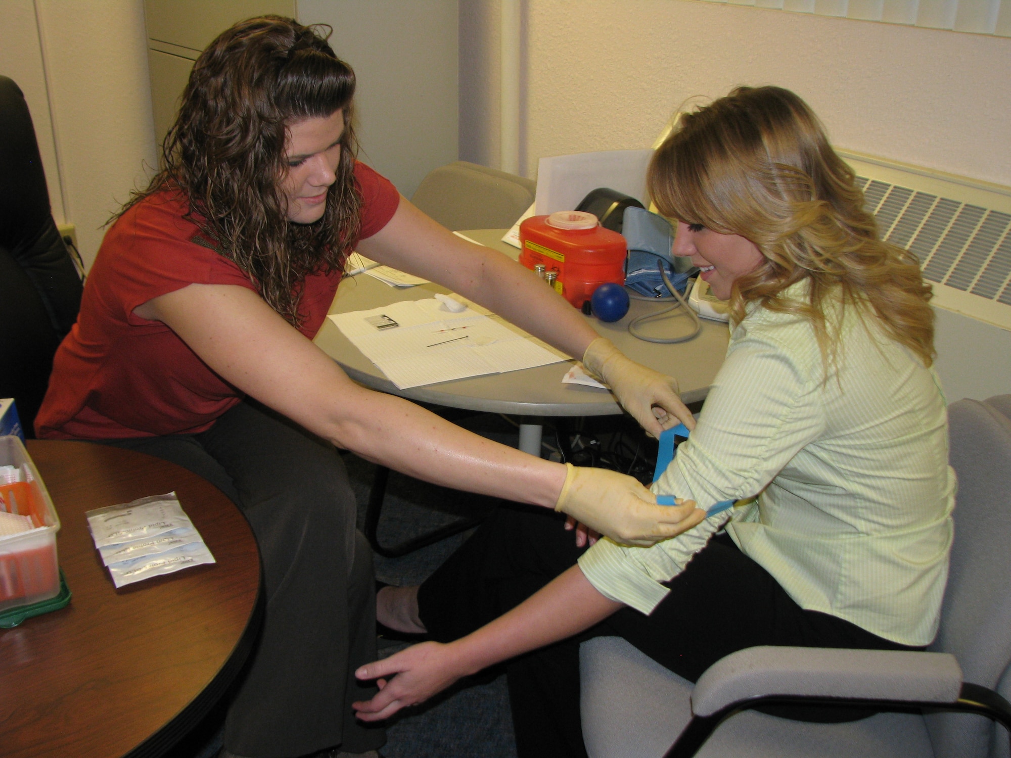 Amber Schwall, Civilian Health Promotion Services Health Promotion coordinator, prepares her first client of the day, Monika Hansing, for a cholesterol screening. (Air Force photo by Diane Betzler)