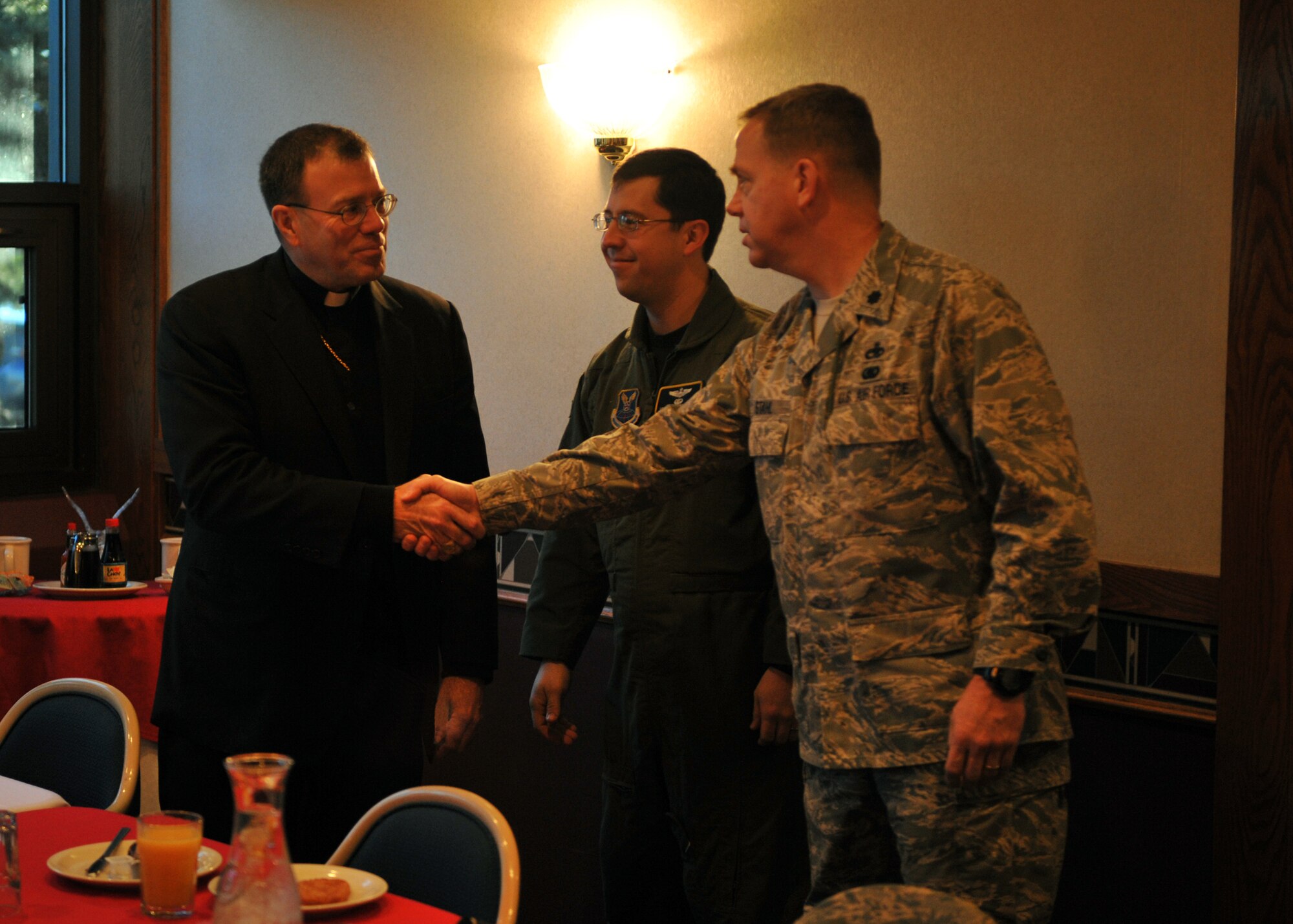 MINOT AIR FORCE BASE, N.D. – Neal Buckon, Auxiliary Bishop for the Archdiocese of military services, greets Lt. Col. William Stahl, 5th Bomb Wing plans and programs chief of operations, and Maj. Jose Castaneda, 5th BW plans and programs chief of nuclear plans and exercises, during a breakfast at the Dakota Inn dining facility here March 31. Bishop Buckon visited Minot to preside over the Catholic Church’s annual confirmation ceremony. (U.S. Air Force photo/Staff Sgt. Keith Ballard)