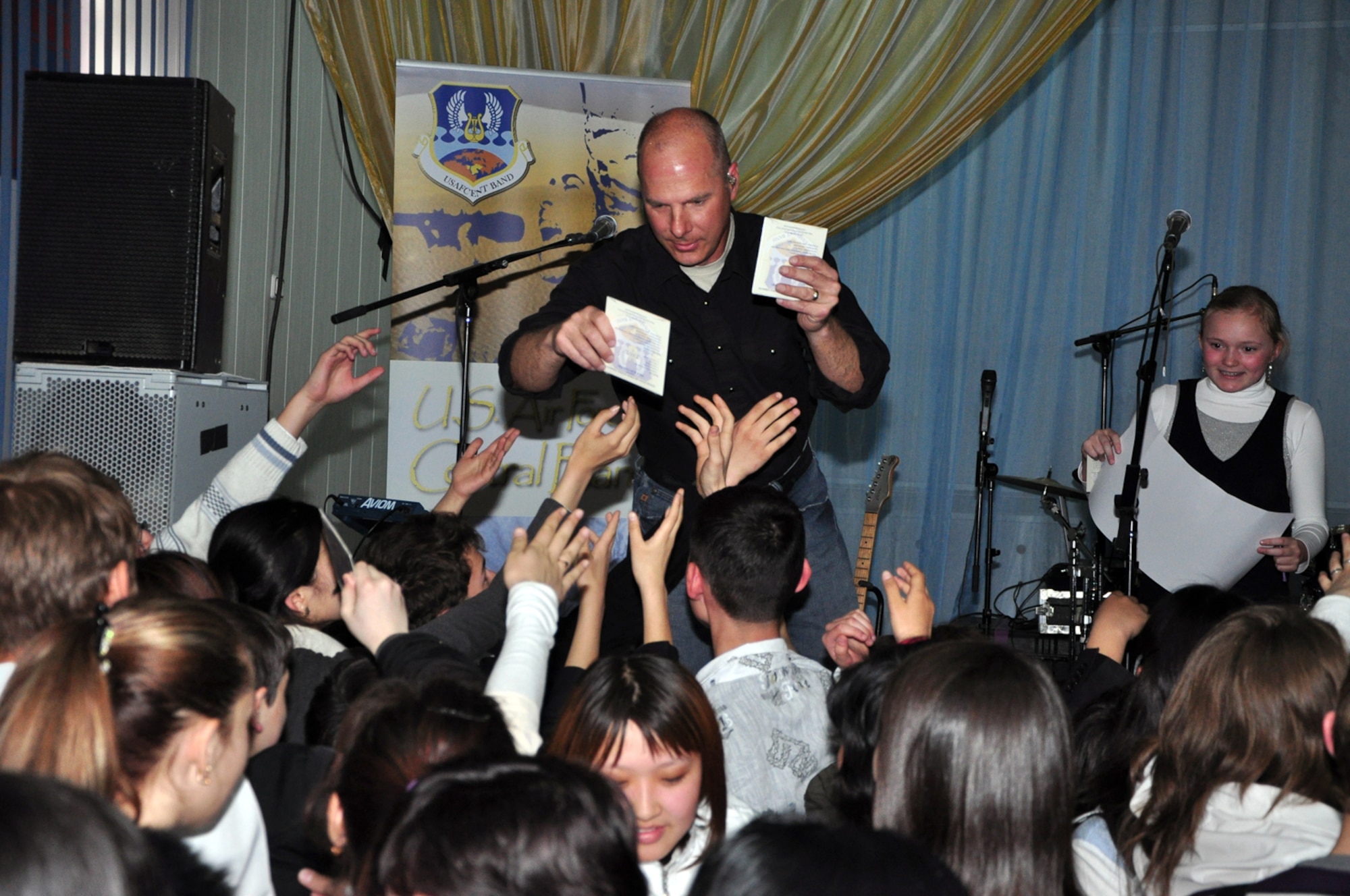 Tech. Sgt. Stephen Brannen passes out CDs of the music of Wild Blue Country to eager students from School-Gymnasium #62 April 1. Wild Blue Country, the current AFCENT band deployed to the Central Command Area of Responsibility, is currently on tour in the Republic of Kyrgyzstan. The band hails from Peterson Air Force Base, Colorado Springs, Colo. (U.S. Air Force photo/Master Sgt. Daniel Nathaniel)