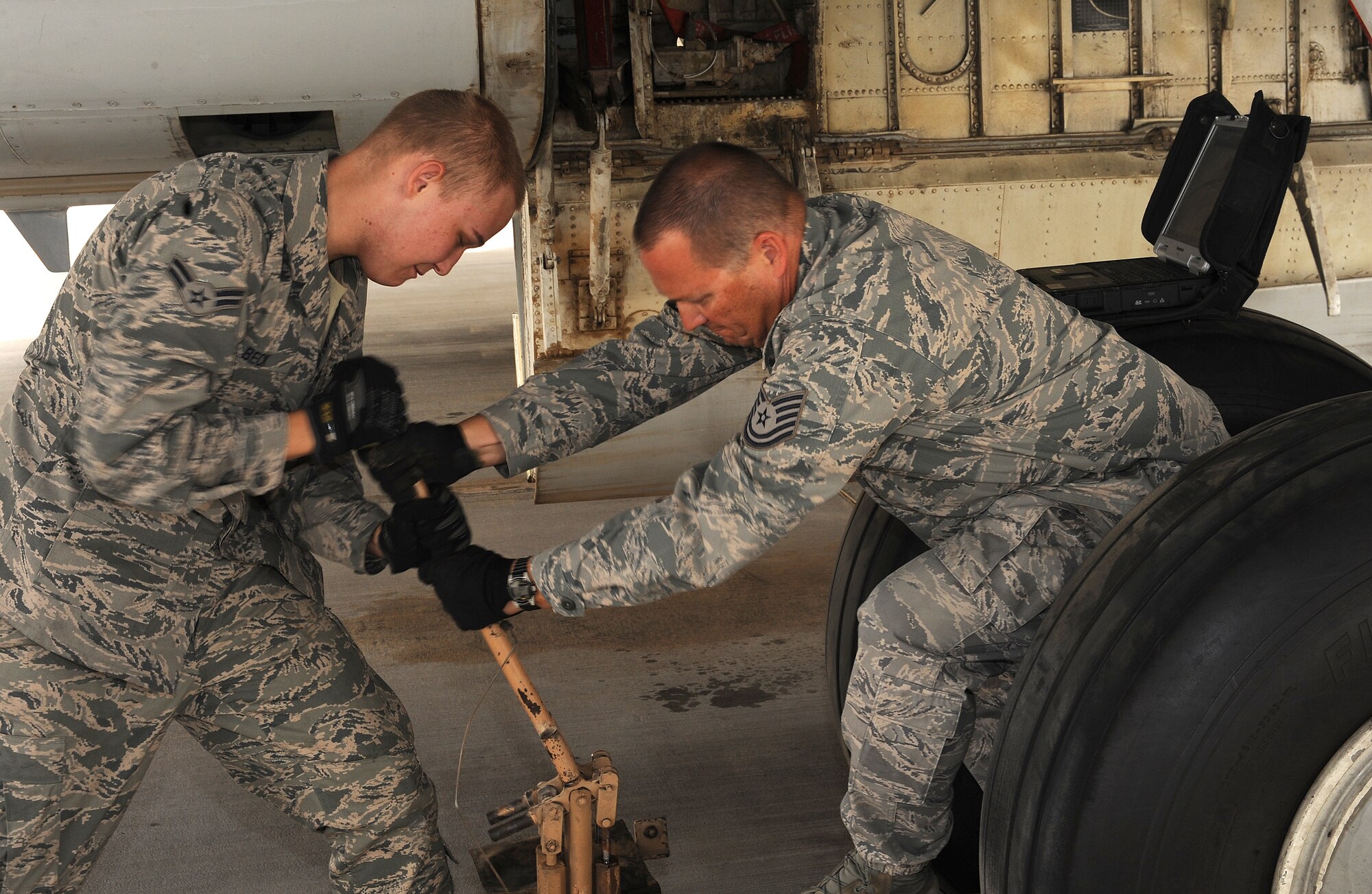 Airman 1st Class Kyle Beck and Tech. Sgt. Al Beck, 7th Expeditionary Aircraft Maintenance Unit,  raise the main gear axle on an E-8 Joint Surveillance Attack Radar System aircraft at an undisclosed location in Southwest Asia, March 31.  (U.S. Air Force photo/Staff Sgt. Liliana Moreno)                                  