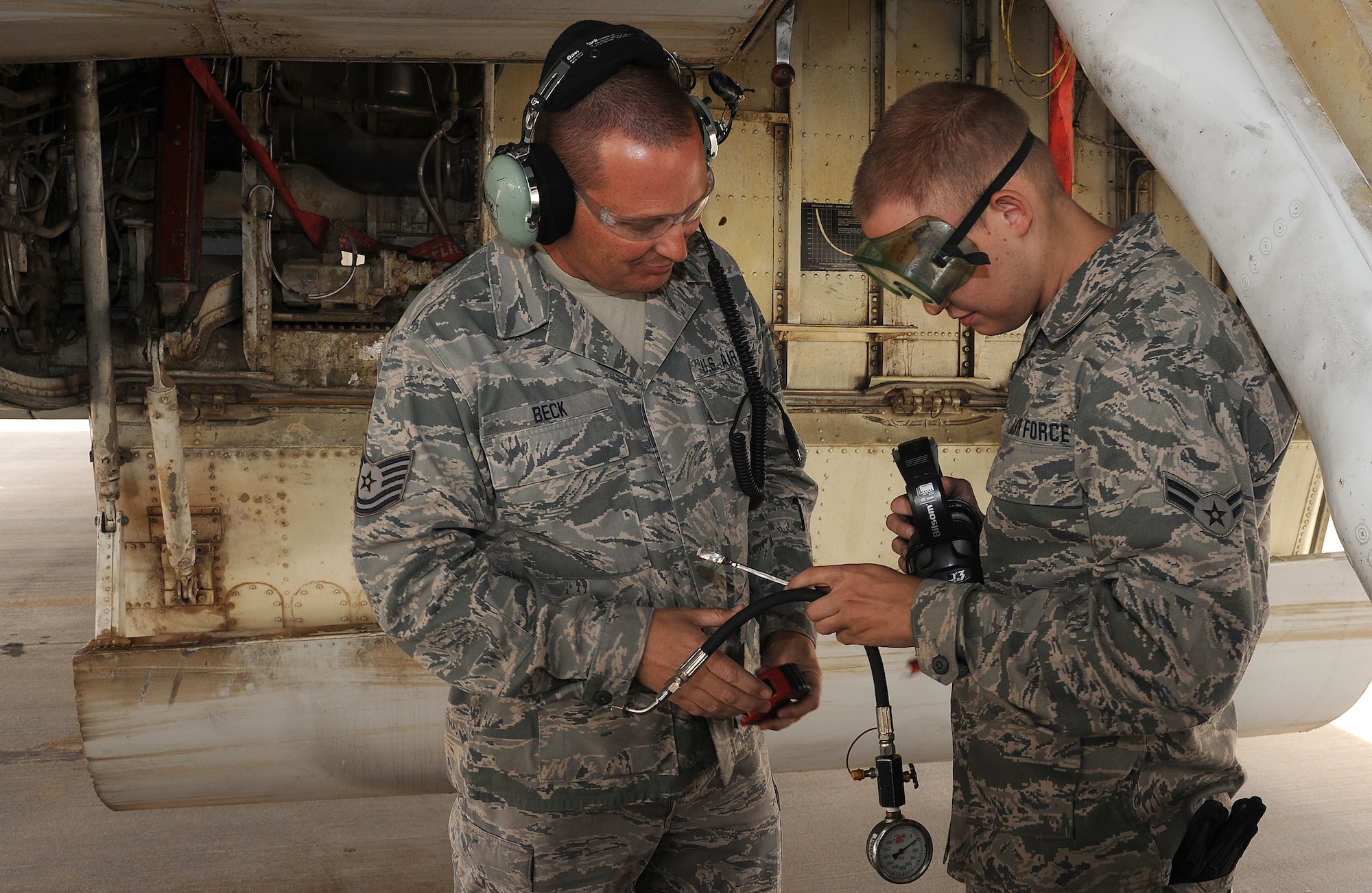 Tech. Sgt. Al Beck and Airman 1st Class Kyle Beck, 7th Expeditionary Aircraft Maintenance Unit, measure the pressure inside a strut on an  E-8 Joint Surveillance Attack Radar System aircraft at an undisclosed location in Southwest Asia, March 31.  (U.S. Air Force photo/Staff Sgt. Liliana Moreno)                              