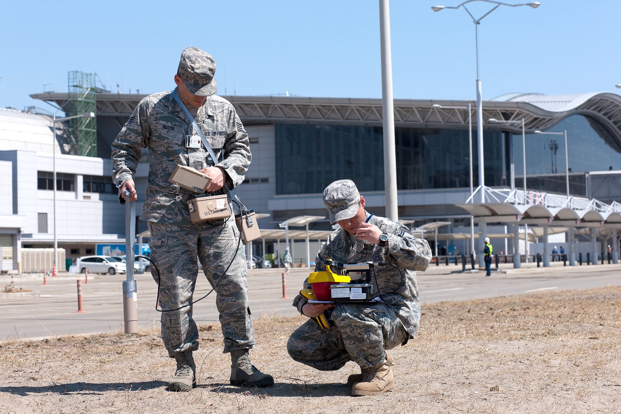 SENDAI AIRPORT, Japan -- Staff Sgt. Kevin Rivera (left) and Senior Master Sgt. Dean Kim, from the Air Force Radiation Assessment Team, use a sodium iodide detector to check for radiation at Sendai Airport, April 5, 2011.  Sergeant Rivera and Sergeant Kim checked for radiation in the air, soil and vegetation. The AFRAT provides commanders and other key decision-makers with risk-based recommendations to maximize force protection while meeting critical mission requirements. (U.S. Air Force photo/Osakabe Yasuo)  
