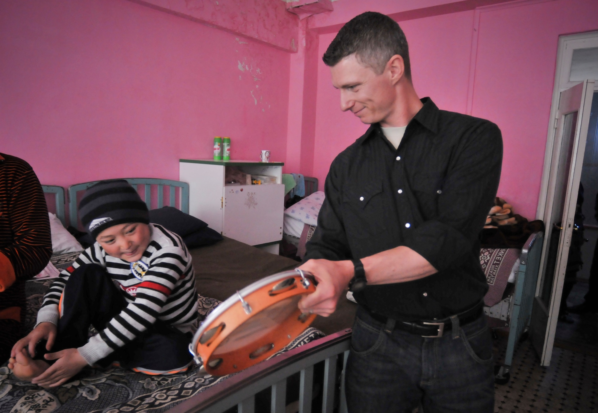 BISHKEK, Kyrgyzstan -  Technical Sgt. Tim Strombaugh from the  AFCENT band "Wild Blue Country" teaches a child how to play the tambourine during a visit to the Children's Cancer Center in Bishkek the band performed for the staff, parents and children there, on April 3.  Band members and members from the Transit Center at Manas played with and gave out gifts to the children.  (U.S. Air Force photo/Staff Sgt. Stacy Moless)

