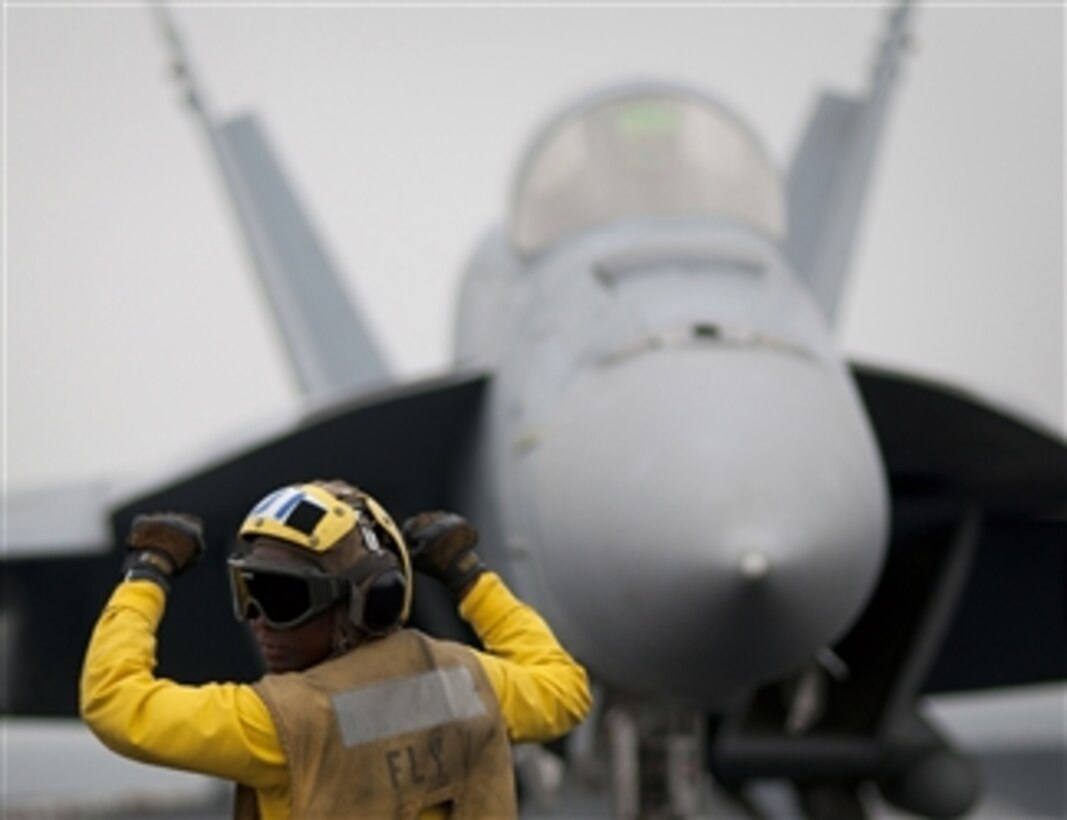 Airman Tamara Sewell directs an F/A-18E Super Hornet aircraft aboard the aircraft carrier USS Carl Vinson (CVN 70) underway in the Arabian Gulf on April 5, 2011.  The Carl Vinson and Carrier Air Wing 17 are conducting maritime security operations and close-air support missions in the U.S. 5th Fleet area of responsibility.  