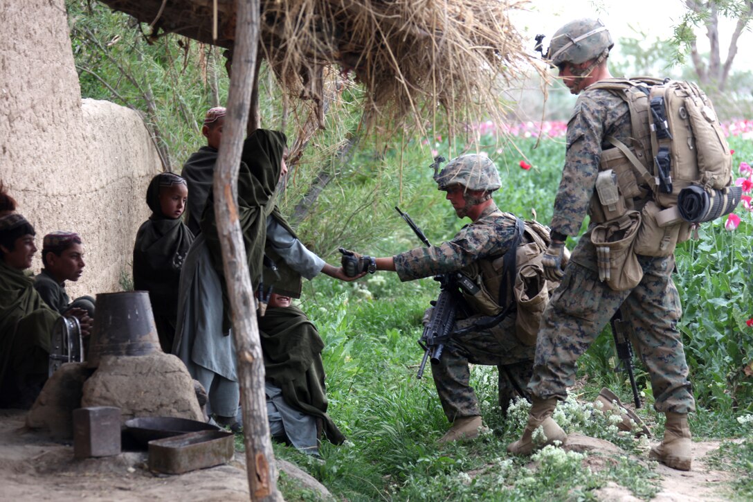 U.S. Marine Corps Lance Cpl. Timothy Brown (center), a team leader, and Navy Hospitalman Chris Coughlin, a corpsman (right), both with 1st Platoon, Company I, Battalion Landing Team 3/8, Regimental Combat Team 8, give candy to Afghan children during a security patrol from their patrol base in Helmand province's Green Zone, west of the Nahr-e Saraj canal, April 7, 2011. Elements of 26th Marine Expeditionary Unit deployed to Afghanistan to provide regional security in Helmand province in support of the International Security Assistance Force.