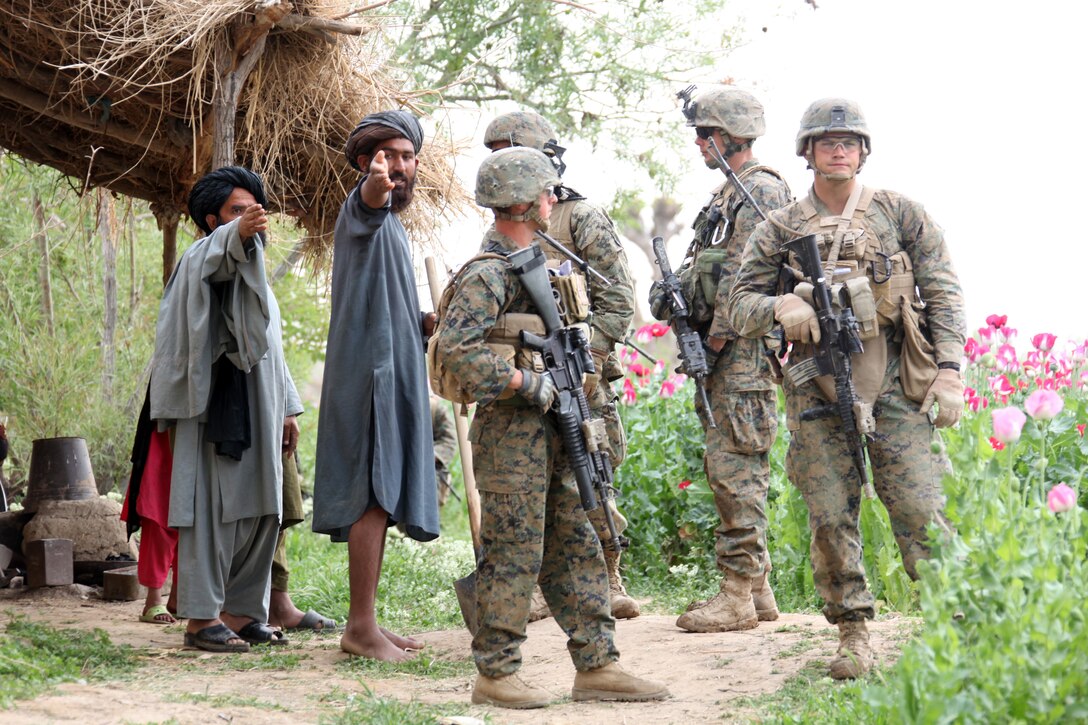 U.S. Marines Sgt. Eric Stump (right to left), Staff Sgt. Gregory Dillon, their Afghan interpreter, and Lance Cpl. Timothy Brown, all with Company I, Battalion Landing Team 3/8, Regimental Combat Team 8, talk to Afghan poppy farmers during a security patrol from their patrol base in Helmand province's Green Zone, west of the Nahr-e Saraj canal, April 7, 2011. Elements of 26th Marine Expeditionary Unit deployed to Afghanistan to provide regional security in Helmand province in support of the International Security Assistance Force.