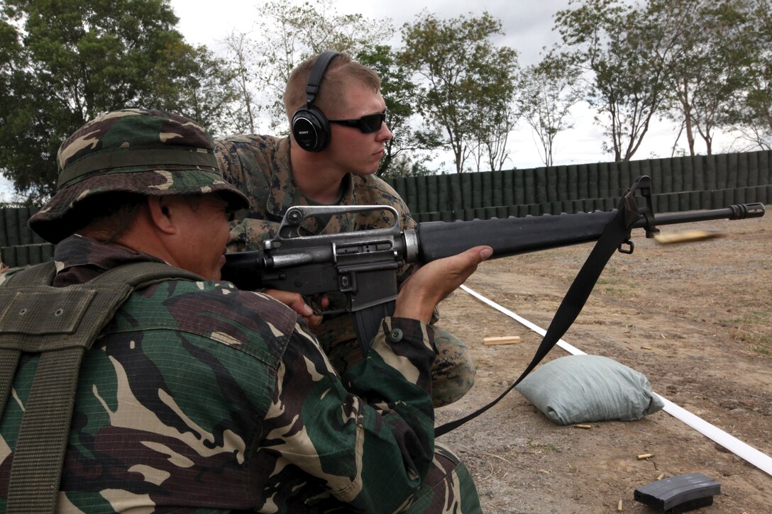 Lance Cpl. Roy Arnold, a military policeman with Military Police Company, Headquarters Battalion, 3rd Marine Division, III Marine Expeditionary Force, watches as Cpl. Rolden Dematera, a soldier with the Philippine National Army, fires his weapon during marksmanship training at Range 1 on Fort Magsaysay April 7 during Exercise Balikatan 2011. The soldiers went through a modified course of fire to test their marksmanship skills.