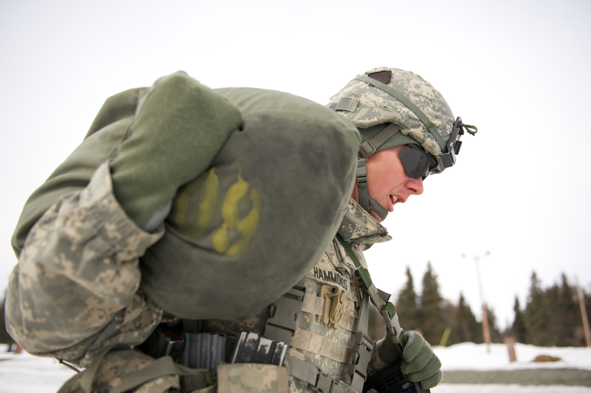 JOINT BASE ELMENDORF-RICHARDSON, Alaska ? Sgt. Michael Hammonds, A Company, 1st Battalion, 501st Infantry Regiment (Airborne), shoulders an 80-pound duffel bag for a 200-meter run during the company's March 24 stress shoot at the Joint Base Elmendorf-Richardson range. (U.S. Air Force photo by David Bedard/Released)