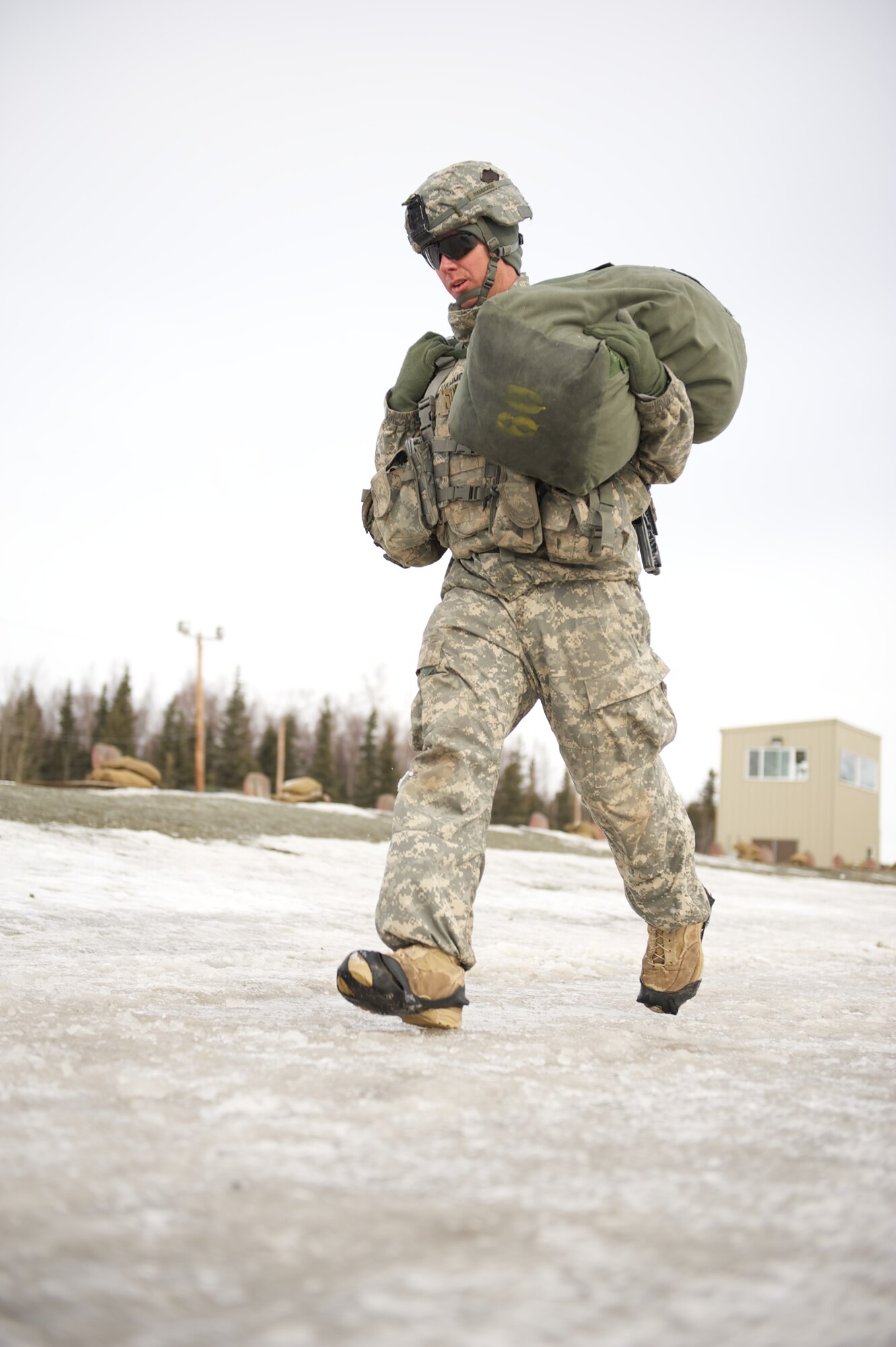 JOINT BASE ELMENDORF-RICHARDSON, Alaska ? Sgt. Michael Hammonds, A Company, 1st Battalion, 501st Infantry Regiment (Airborne), shoulders an 80-pound duffel bag for a 200-meter run during the company's March 24 stress shoot at the Joint Base Elmendorf-Richardson range. (U.S. Air Force photo by David Bedard/Released)