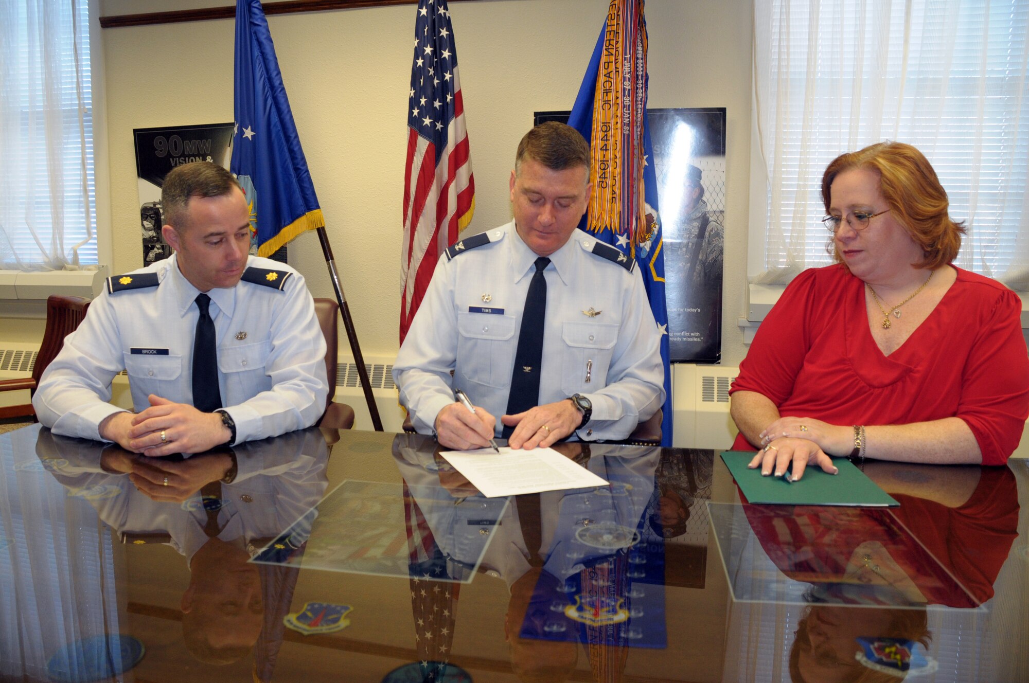 Col. Greg Tims, 90th Missile Wing commander signs the Crime Victim Rights Week proclamation announcing the week of April 24 through 30 to be designated as F. E. Warren Crime Victim Rights Week as Maj. Allan Brock and Bonnie Scotto, both 90th MW Judge Advocate’s office, look on April 4. (U.S. Air Force photo by Blaze Lipowski)