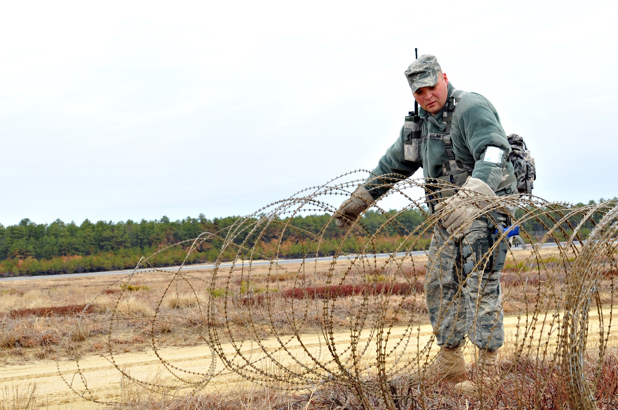 JOINT BASE MCGUIRE-DIX-LAKEHURST, N.J. -- Staff Sgt. Eric Drabinowicz, 570th Global Mobility Readiness Squadron, lays out c-wire to set up an entry control point to the base during EAGLE FLAG April 4. The Air Force, 570th Contingency Response Group, Travis Air Force Base, Calif., and the Army, 689th Rapid Port Opening Element, Joint Base Langley-Eustis, Va., worked together to build a bare base for humanitarian relief efforts during EAGLE FLAG conducted by the U.S. Expeditionary Center. (U.S. Air Force photo by Wayne Russell/Released)