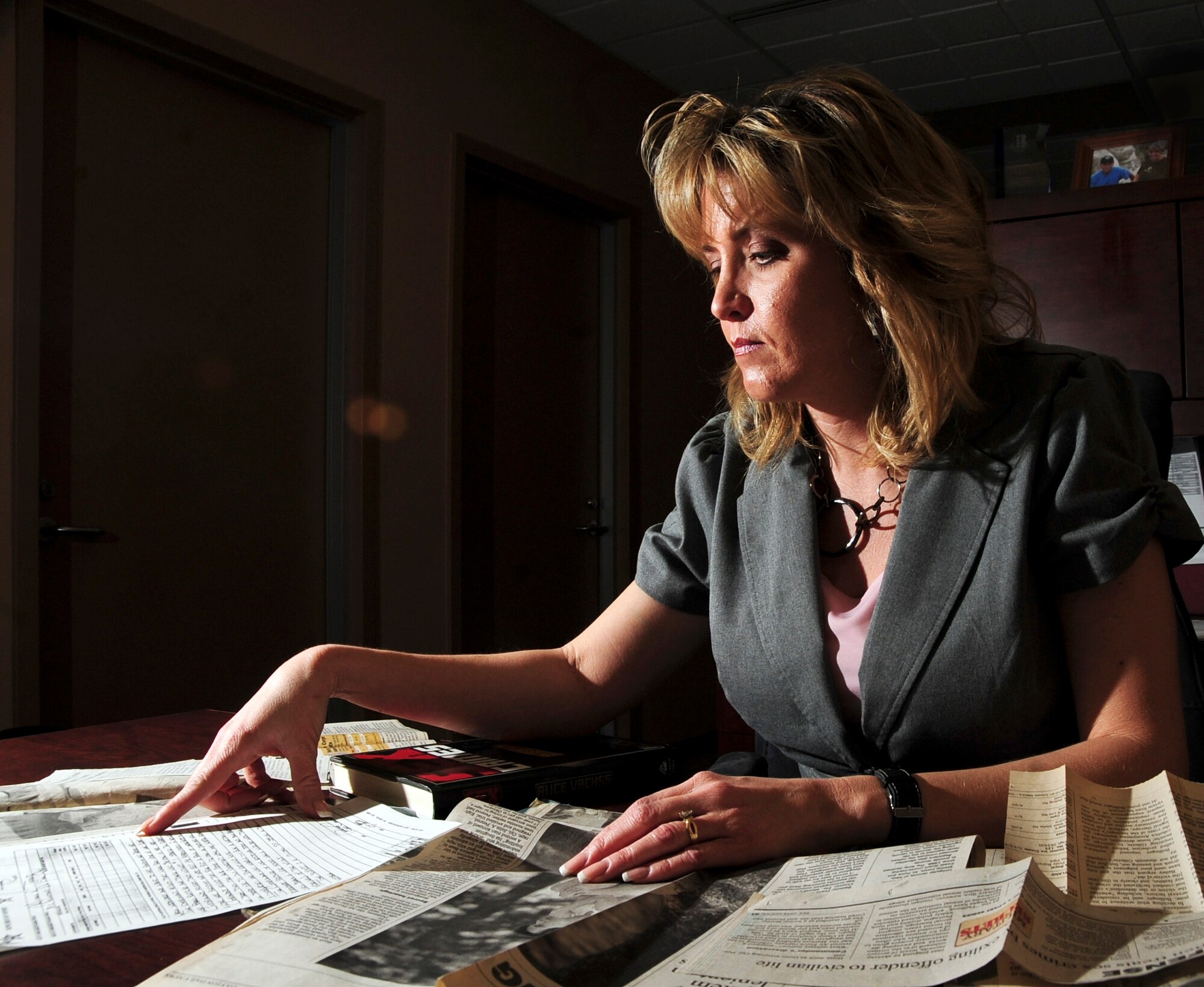 Michele Rogers, 28th Bomb Wing protocol specialist, at Ellsworth Air Force Base, S.D., looks at newspaper clippings and court notes April 05, 2011, related to her  sexual assault. The crime, which took place nearly 18 years ago while she was stationed at Wright-Patterson Air Force Base, Ohio., led to the removal of a senior airman from the Air Force. (U.S. Air Force photo/Senior Airman Adam Grant)