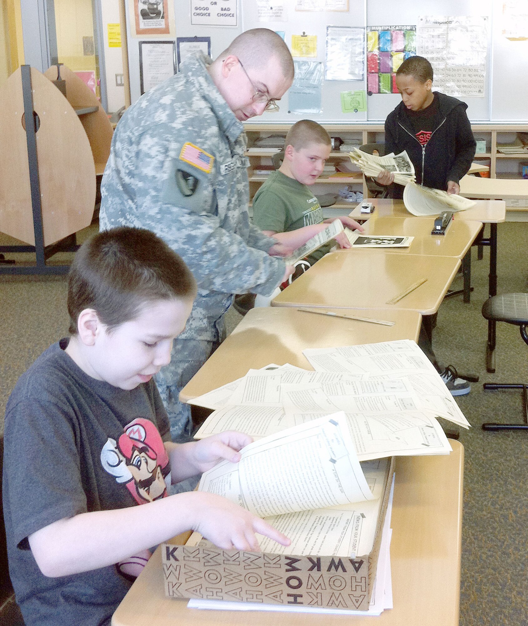Sgt. Isaac Reighard, 56th Engineer Company, 6th Engineer Battalion (Airborne), assists three fifth-grade students as they assemble a monthly school newsletter, at
Chester Valley Elementary School, Feb. 28. Several Soldiers from the 56th volunteer
at the school through the U.S. Army Alaska and Anchorage School District Partnership
Program. (Courtesy photo)