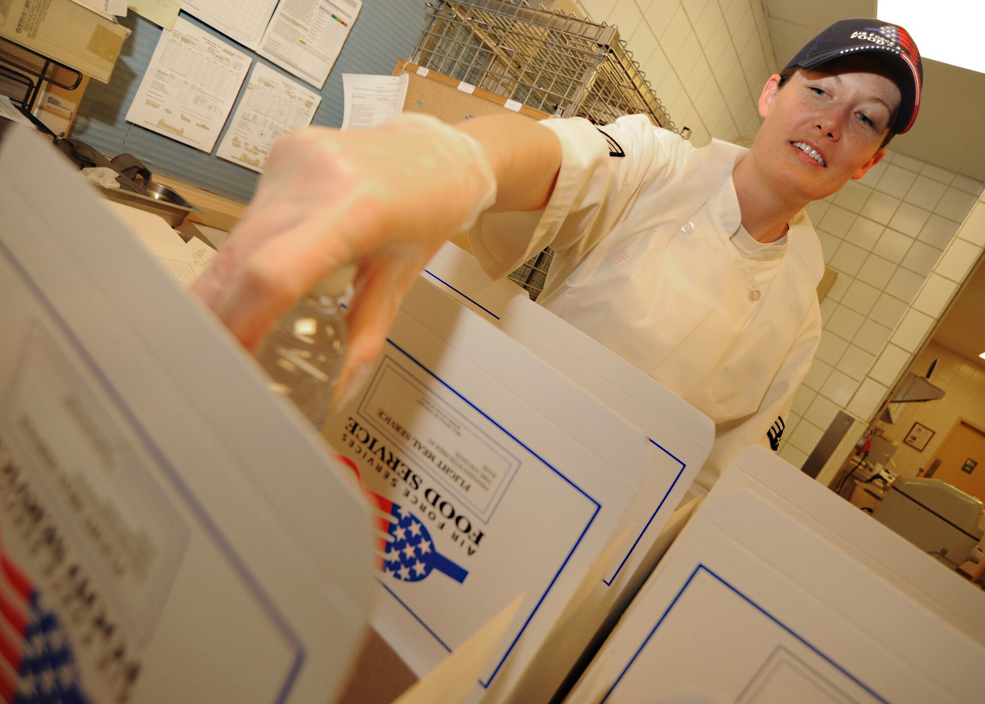 Senior Airman Amy Dunn-Watkins, 22nd Force Support Squadron shift leader, places a bottled water inside a box lunch at the Flight Kitchen in the Chisholm Trail Inn dining facility April 5, 2011, McConnell Air Force Base, Kan. The DFAC serves approximately 400 people a day. DFAC Airmen work alongside contractors to efficiently keep up with base meal needs. Contractors also help with extra duties at the DFAC when Airmen are deployed. (U.S. Air Force photo/Senior Airman Maria A. Ruiz)