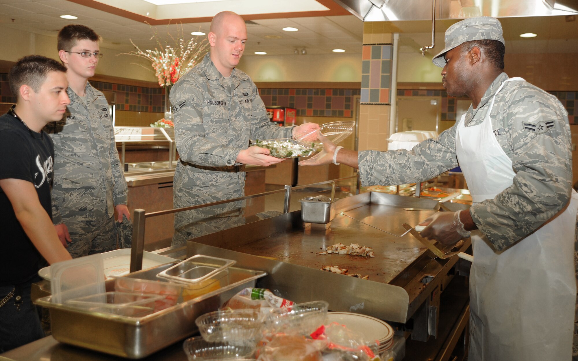 Airman 1st Class Mohamed Berete, 22nd Force Support Squadron services apprentice, hands a salad to Airman 1st Class Joshua Houseworth, 22nd Contracting Squadron contracting specialist, at the Chisholm Trail Inn Dining Facility April 5, 2011, McConnell Air Force Base, Kan. DFAC Airmen work eight hour shifts as part of its 24-hour operations, and usually have two or three Airmen working each shift. Services Airmen are trained in protocol, lodging, fitness services, squadron readiness and mortuary affairs at Dover Air Force Base, Del. (U.S. Air Force photo/Senior Airman Maria A. Ruiz)