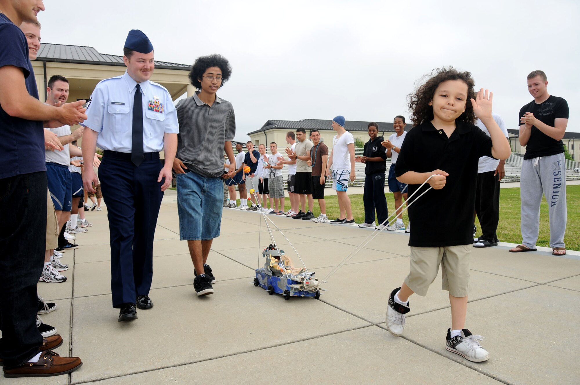 From left, Master Sgt. Chad Chapman, 81st Mission Support Group, and son Jonathan, 16, follow Sergeant Chapman’s 6-year-old son Christien, who pulls his StarWars shoebox float while waving to a crowd of training students lining the drill pad behind the Levitow Training Support Facility. Monday’s parade featured children cared for by the base’s family child care providers and is part of Keesler’s Month of the Military Child observance. Sergeant Chapman’s wife, Maria, is a family child care provider.  (U.S. Air Force photo by Kemberly Groue)
