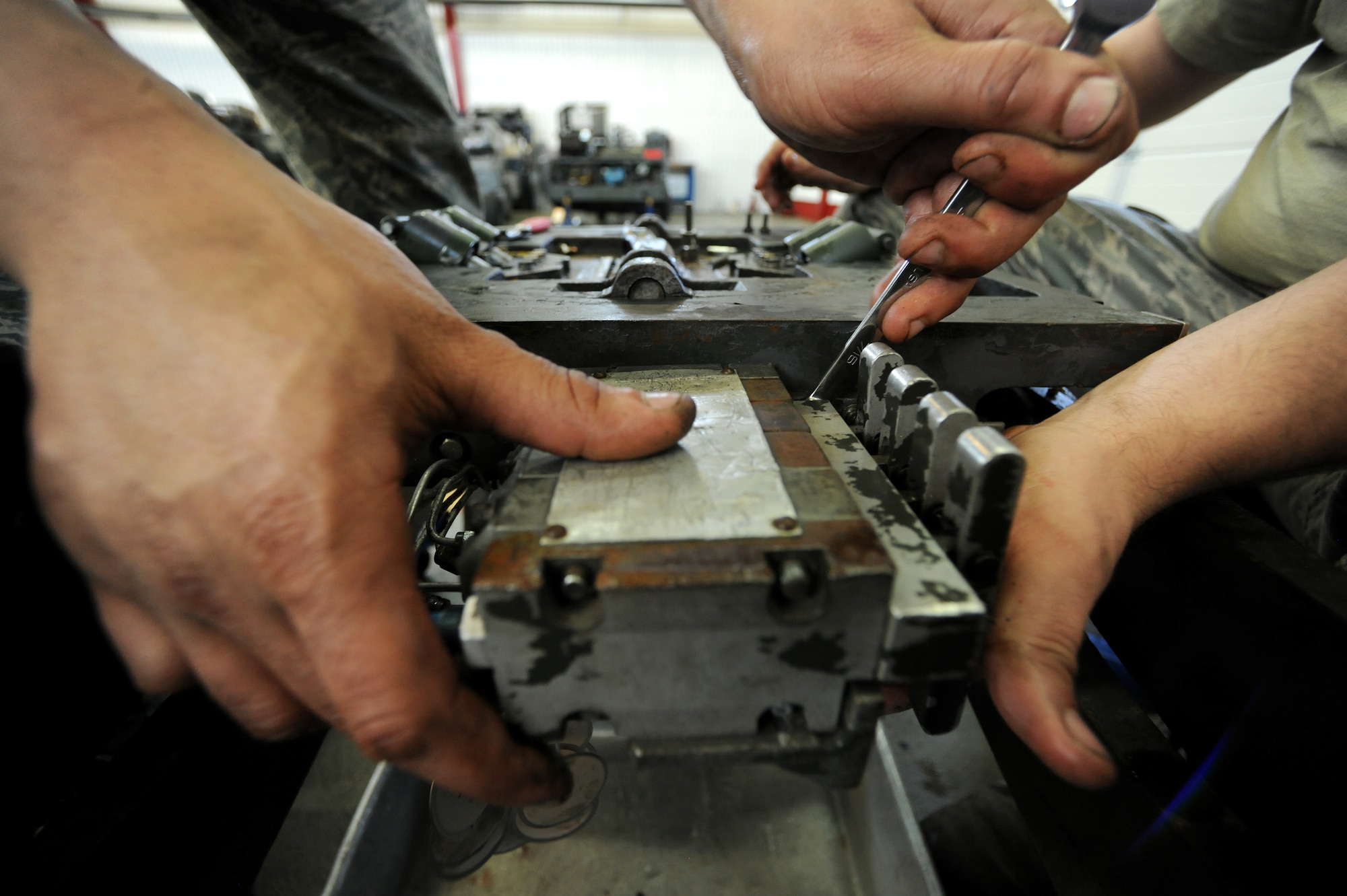 SPANGDAHLEM AIR BASE, Germany – Airman 1st Class Gary Hutchison and Senior Airman Blake Skaggs, 52nd Equipment Maintenance Squadron aerospace ground equipment journeymen, remove bolts attaching a directional control valve to a MJ-1B bomb lift here April 7. The directional control valve controls the tilt and movement of the lift table enabling weapons loaders to make minuscule adjustments to munitions during the load process. The control valve has four manifolds, each controlling a specific function of the load plate. (U.S. Air Force photo/Senior Airman Nathanael Callon)