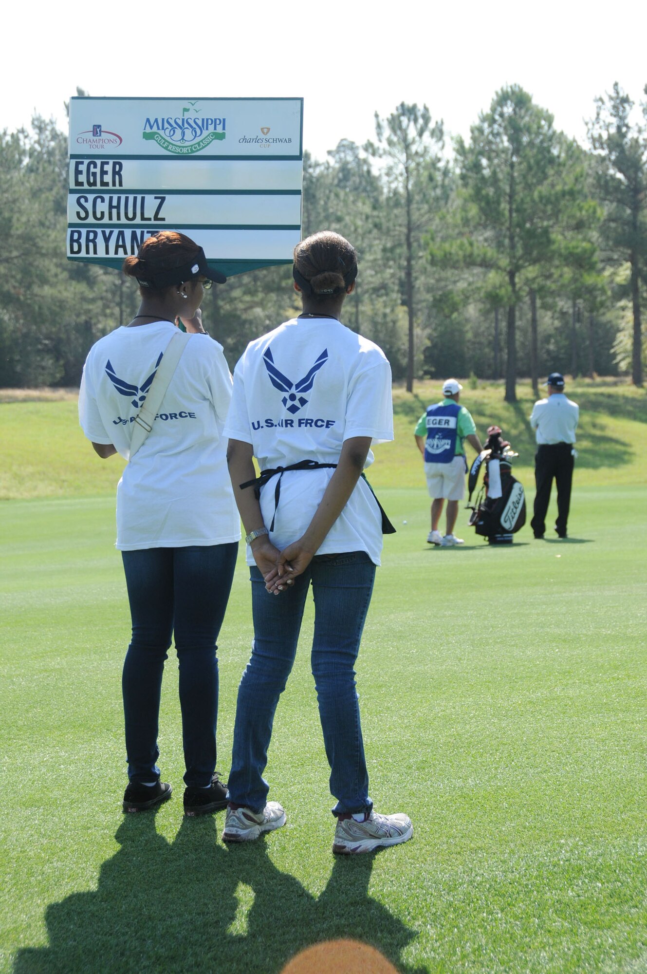Airmen Basic Alexis Rogers, left, and Angel Mingo, student volunteers from the 336th Training Squadron, hold a walking score sign for golfers Friday during the opening day of the Mississippi Gulf Resort Classic at Fallen Oak Golf Club in Saucier. Friday was also Military Appreciation Day, offering free admission to anyone with a military ID card and their family members. About 300 Keesler volunteers assisted with the PGA Champions Tour event, now in its second year, with Tom Lehman winning the title.  (U.S. Air Force photo by Kemberly Groue)