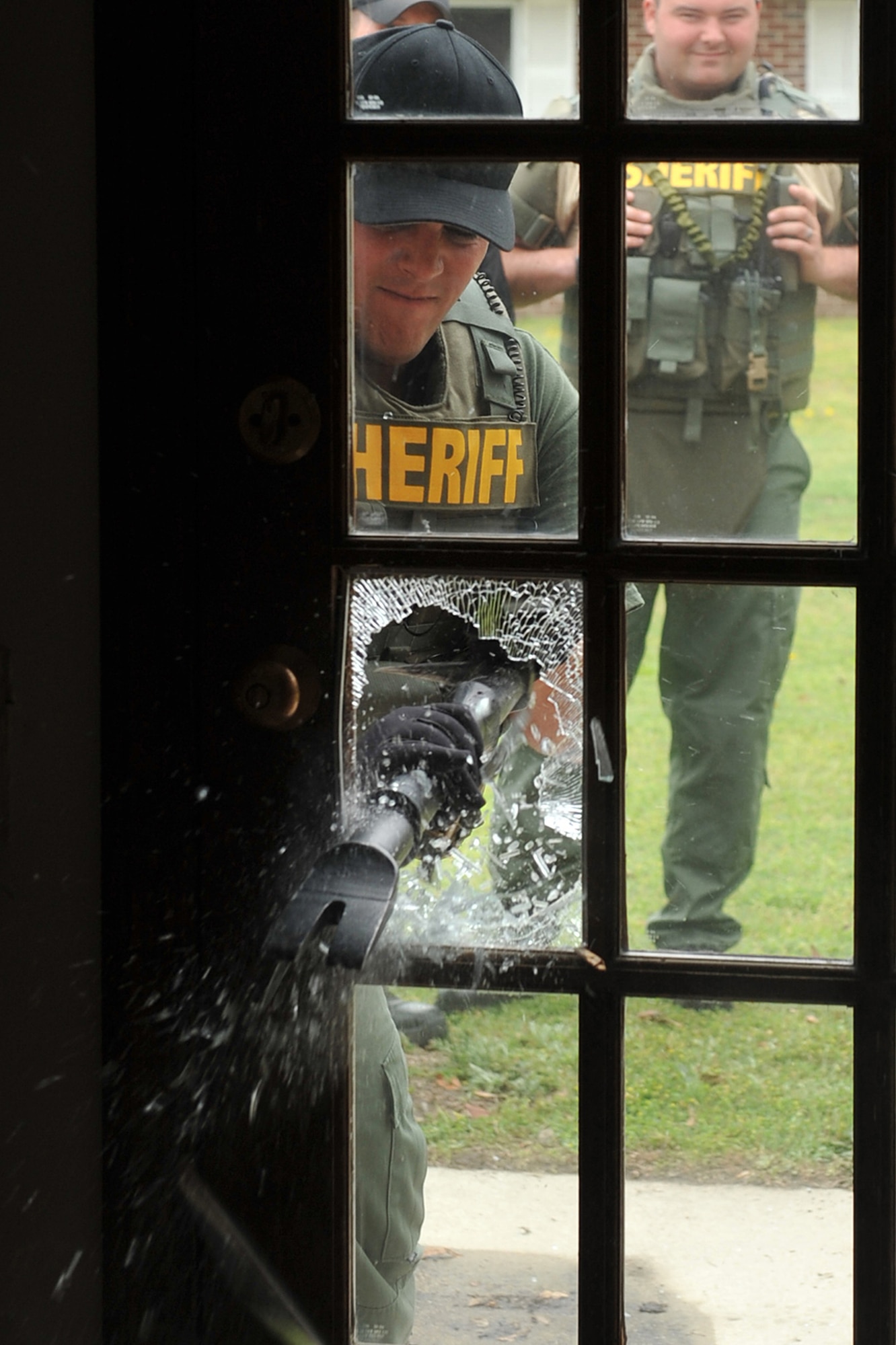 SEYMOUR JOHNSON AIR FORCE BASE, N.C.-- A Duplin County Sheriff's Office special response team member uses a halogen tool to break through a glass door here in base housing, April 5, 2011. This was the first time Duplin County Sheriff's Office special response team trained with members of the 4th Security Forces Squadron. The sheriff's office team is located in Kenansville. (U.S. Air Force photo/Senior Airman Whitney Lambert) (RELEASED)