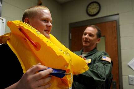 Lt Col Mike Phillips adjusts a life vest that freshman, Cody Frakes was given the oppurtunity to try on during a school visit to Ashley Ridge High School on April 5.  Colonel Phillips is a part of the Air Mobility Command Demonstration team is scheduled to perform an air drop at the 2011 Air Expo on April 8.  Colonel Phillips is a C-17 pilot with the 16th Airlift squadron.  He and Staff Sgt. Scott Skinner, a loadmaster from the 15th Airlift Squadron, explained thier jobs to 9th and 10th grade JROTC students during the school visit.  (U.S. Air Force photo/ Staff Sgt. Nicole Mickle)  (Released)