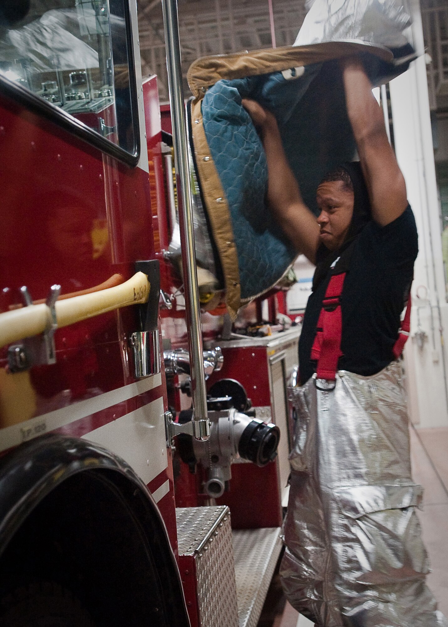 YOKOTA AIR BASE, Japan -- Airman 1st Class Darryl Mosby, 374th Civil Engineer Squadron firefighter, puts on proximity gear here April 7, 2011. Firefighters have approximately one minute to gear-up and be strapped on the fire truck. Yokota Airmen continually train in order to assist the Japanese with relief efforts following the earthquake and tsunami that struck March 11. (U.S. Air Force photo/Airman 1st Class Andrea Salazar)