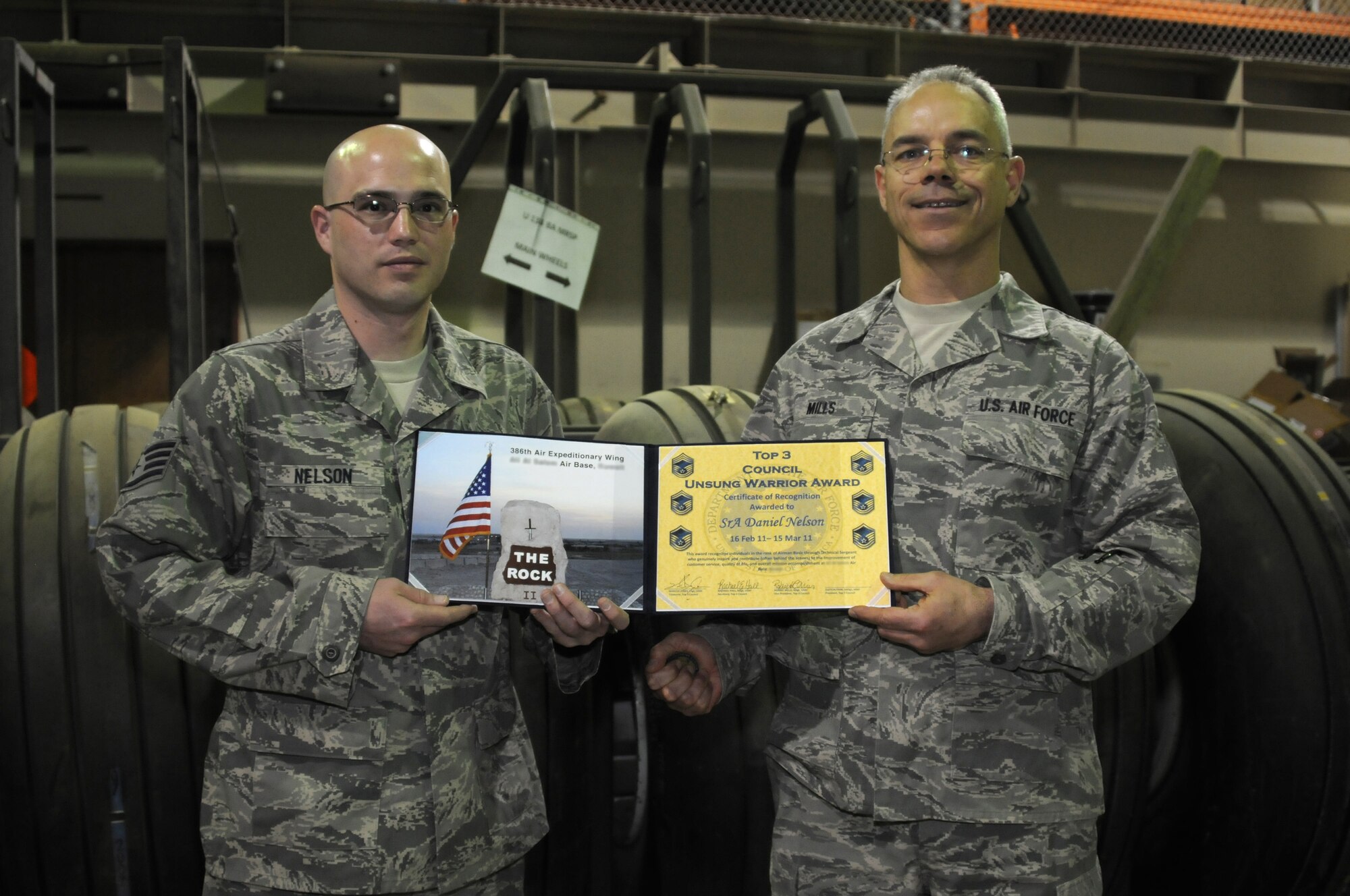 Master Sgt. Robert Mills, vice president of The Rock Top III, right, presents the Unsung Warrior Award - Airman category to Staff Sgt. Daniel Nelson April 6 at the 386th Air Expeditionary Wing's aircraft parts supply store. Sergeant Nelson, who was promoted to staff sergeant April 1, won the award for his accomplishments as a senior airman with the 386th Expeditionary Logistics Readiness Squadron February 15-March 15. (U.S. Air Force photo by Capt. Heath Allen)