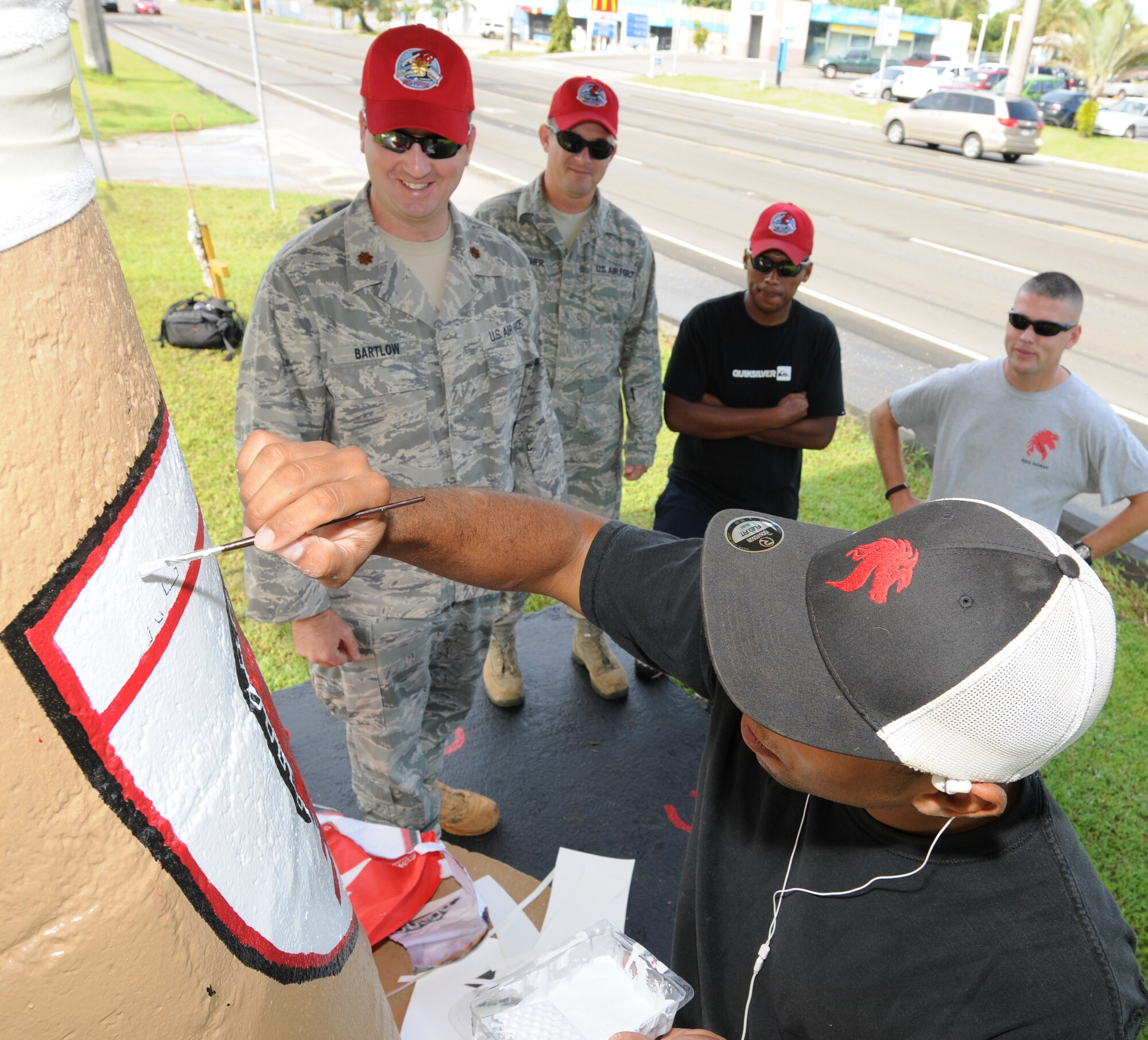 ANDERSEN AIR FORCE BASE, Guam - Co-workers watch as Staff Sgt. Cameron
Pleasant, 554th RED HORSE Squadron structures shop, creates a work of art
using the squadron's emblem, April 7. Sergeant Pleasant dedicated more than
five hours to paint his piece of the bus stop the RED HORSE squadron has
adopted within the local community. (U.S. Air Force photo / Senior Airman
Carlin Leslie)
