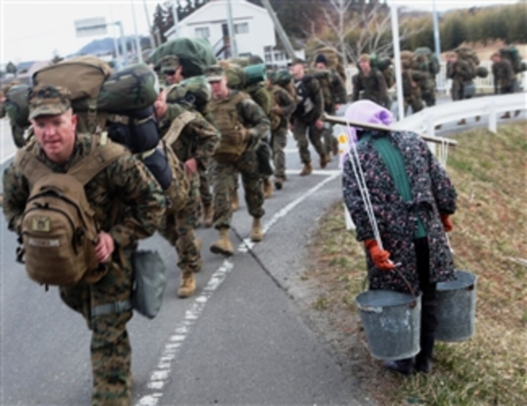 A local woman carrying water bows in thanks to Marines with the command element, 31st Marine Expeditionary Unit, who are on the way to assist with Operation Field Day in Honshu, Japan, on April 4, 2011.  The operation is a debris-clearing and cleanup project designed to open harbor access and area roads on the island.  The 31st Marine Expeditionary Unit is participating in Operation Tomodachi at the request of the Japanese government after the 9.0 earthquake and tsunami devastated the northeast coast of Japan.  