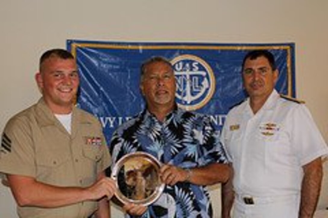 Sgt Price accepts a silver plate from Mark Sablan, president of the Guam chapter of the Navy League of the United States, and Rear Adm. Paul Bushong, commander of Joint Region Marianas during a luncheon honoring the Guam service members of the year.