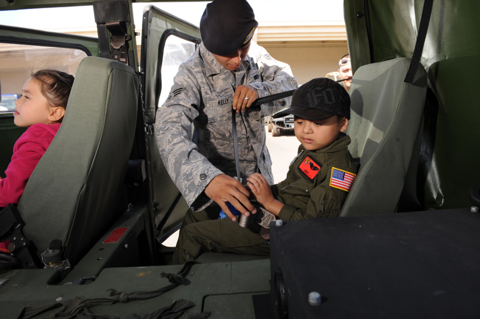 Seven year-old Jonah "J-Boy" Kalakai sits back while 15th Security Forces Squadron Senior Airman Shane Kelly fastens his seatbelt before his ride in a HUMVEE while at the 535th Airlift Squadron, Joint Base Pearl Harbor-Hickam, Hawaii on April 2, 2010. J-Boy was invited to JBPHH to participate in the "Pilot for a Day" program which is a partnership between Kapi'olani Medical Center and the 15th Airlift Wing that gives a special day to a child that is dealing with a serious or chronic condition. J-Boy was diagnosed with Acute Myeloid Leukemia at age two and has been in and out of remission five times since then. (U.S. Air Force photo/Tech Sgt. Cohen A. Young)