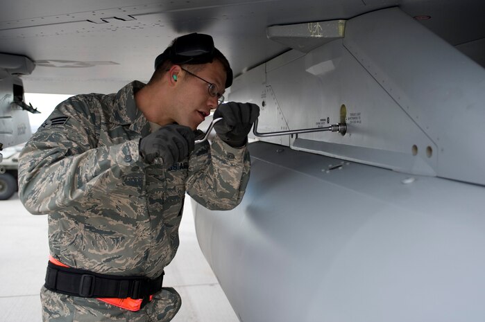 NELLIS AIR FORCE BASE, Nev.-- Senior Airman Lucas Wolf, 57th Aircraft Maintenance Squadron, load crew member, prepares an F-16 for the loading of a Mark-82 bomb during the 1st quarterly weapons load competition April 8. Weapons load competitions are conducted quarterly to keep Airmen sharp and recognize superior performers. Weapons load teams are evaluated for their use of the checklist, safety, and overall speed. (U.S. Air Force photo by Airman 1st Class Matthew Lancaster)