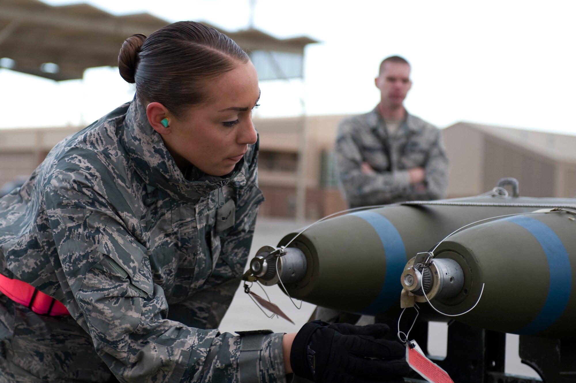 NELLIS AIR FORCE BASE, Nev.-- Airman 1st Class Amanda Schreckengost, 57th Aircraft Maintenance Squadron, load crew member, prepares to loads a Mark-82 bomb onto an F-16 while an evaluator watches during the 1st quarterly weapons load competition April 8. Weapons load competitions are conducted quarterly to keep Airmen sharp and recognize superior performers. Weapons load teams are evaluated for their use of the checklist, safety, and overall speed. (U.S. Air Force photo by Airman 1st Class Matthew Lancaster)