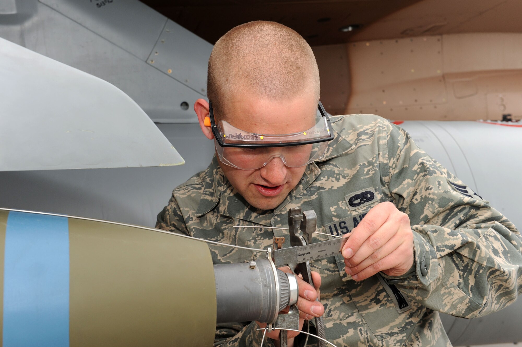 NELLIS AIR FORCE BASE, Nev. --Senior Airman Robert Anderson, a 57th Aircraft Maintenance Squadron weapons load crew member, checks measurements on an arming wire during the quarterly load crew competition here April 8.  Weapons load competitions are conducted quarterly to keep Airmen sharp and recognize superior performers. Weapons load teams are evaluated for use of the checklist, safety, and overall speed. (U.S Air Force photo by Staff Sgt. Taylor Worley)
