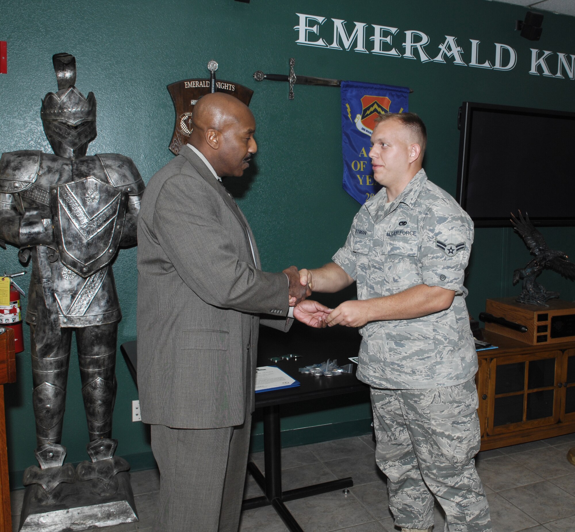 Police Chief Roy Mentor, Peoria Police Department, presents Airman 1st Class Luke Notman, 308th Aircraft Maintenance Unit assistant dedicated crew chief, with a coin April 1 during a recognition ceremony at Luke Air Force Base, Ariz.  Airman Notman was recognized for rendering medical aid and attempting to save the life of a pedestrian March 7 after she was hit by a vehicle (U.S. Air Force photo/Staff Sgt. Steve Nabor)