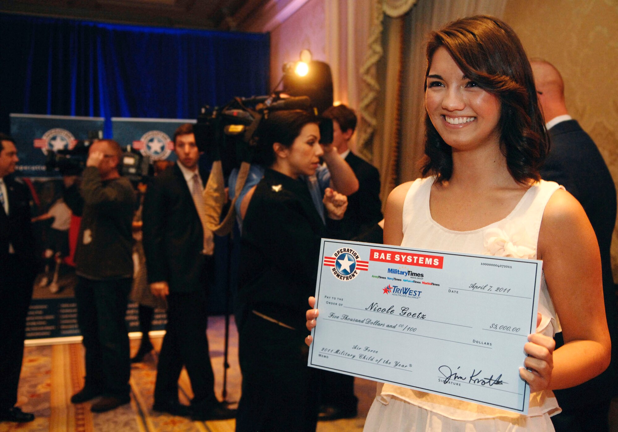 Nicole Goetz, of Tyndall Air Force Base, Fla., holds up an oversized 
check during Operation Homefront's 2011 Military Child of the Year award 
ceremony April 7, 2011, in Arlington, Va. Ms. Goetz is the Air Force's 
award recipient. She is the daughter of Chief Master Sgt. Michael Goetz, who traveled here from Afghanistan to see his daughter get her award in person. Ms. Goetz volunteered at the local youth center, her church, veterans and nursing homes, and joined a variety of high school clubs. She also organized 21 local schools to create and send hundreds of homemade 
Christmas cards, cookies and care packages to troops overseas. A committee of active-duty service members, family readiness support assistants, teachers, military mothers and community members chose the award recipients. The winners received $5,000 and a trip to Washington for the ceremony. (U.S. Air Force photo/Staff Sgt. Tiffany Trojca)
