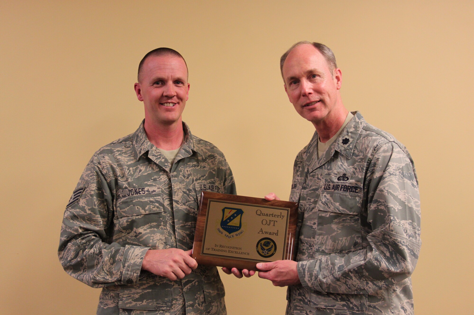 Staff Sgt. Conrad Jones, 310th Force Support Squadron, is accepting 310th Space Wing Quarterly On-The-Job Training award from Lt. Col. Patrick Walsh, 310th Mission Support Group. Sergeant Jones distinguished himself in the large unit competition by meeting every quarterly requirement for unit training managers. Master Sgt. Patrick Hampton (not photographed) also won the 310 SW Quarterly OJT award for small units. (U.S. Air Force photo by Staff Sgt. Desiree Economides)