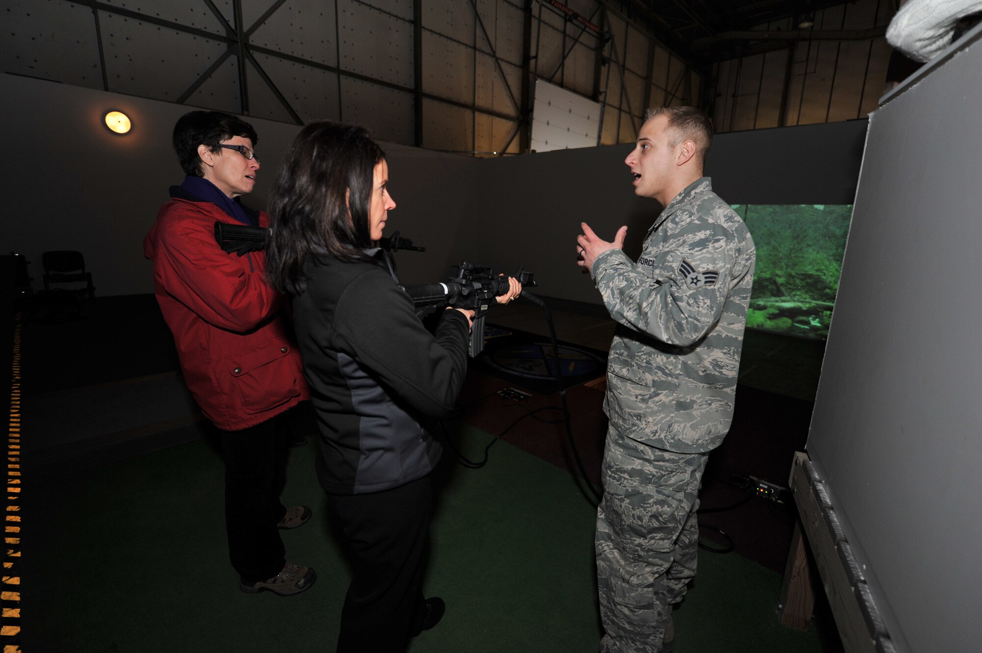 Senior Airman Anthony Pastore, 341st Security Support Squadron training instructor, explains to Nora Flaherty-Gray (left) and Valerie Flaherty what the EST 2000 training range is used for before they try their hands at it.  (U.S. Air Force photo/Beau Wade)